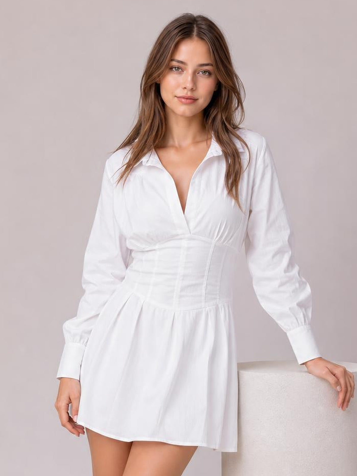 Model poses in a white collared mini dress with long lantern sleeves, ruched corset-style waist, gathered skirt, and relaxed A-line silhouette.