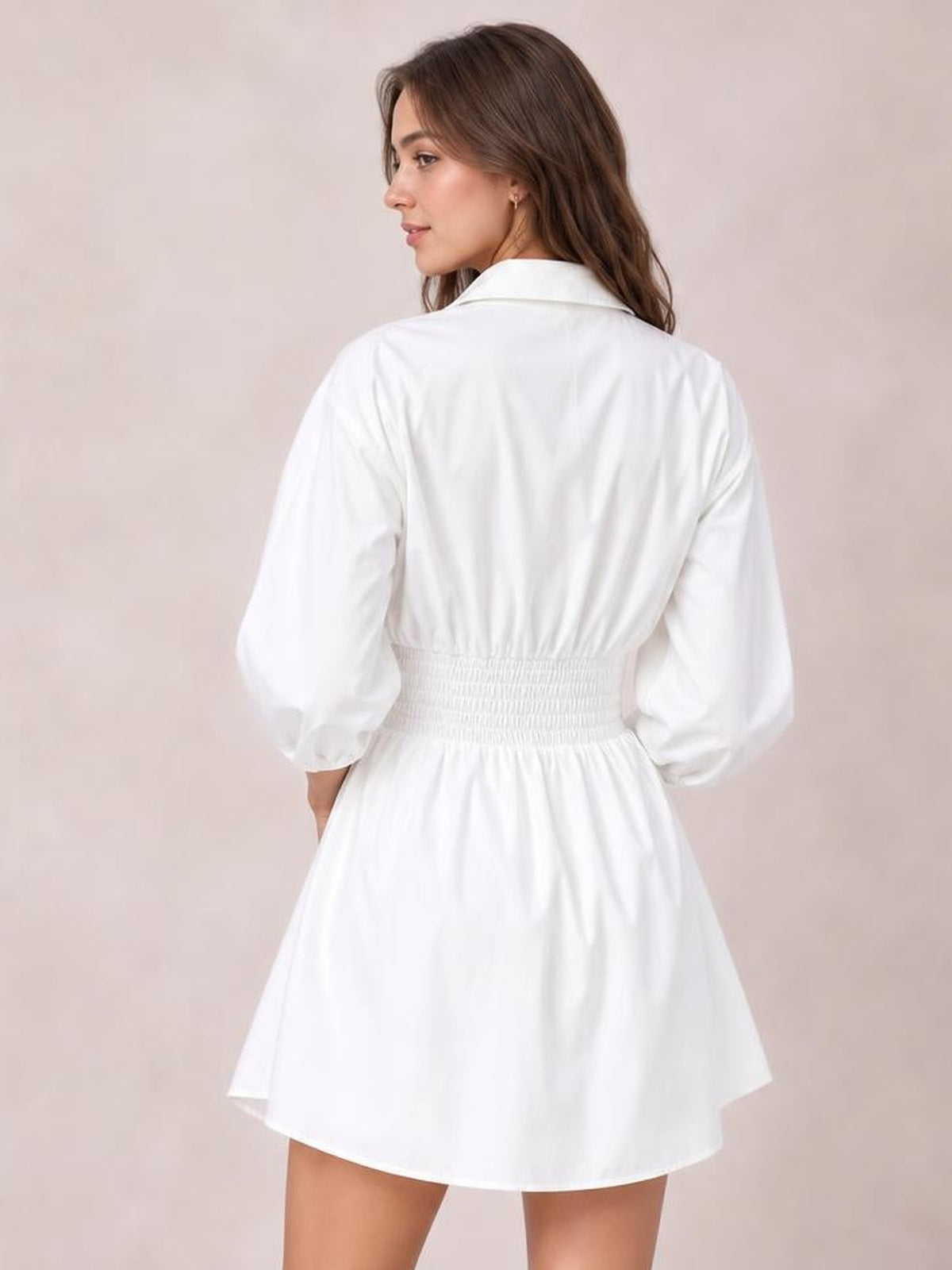 Model poses in a back three-quarter view wearing a white collared mini dress with lantern sleeves, ruched waist, and a flared silhouette.