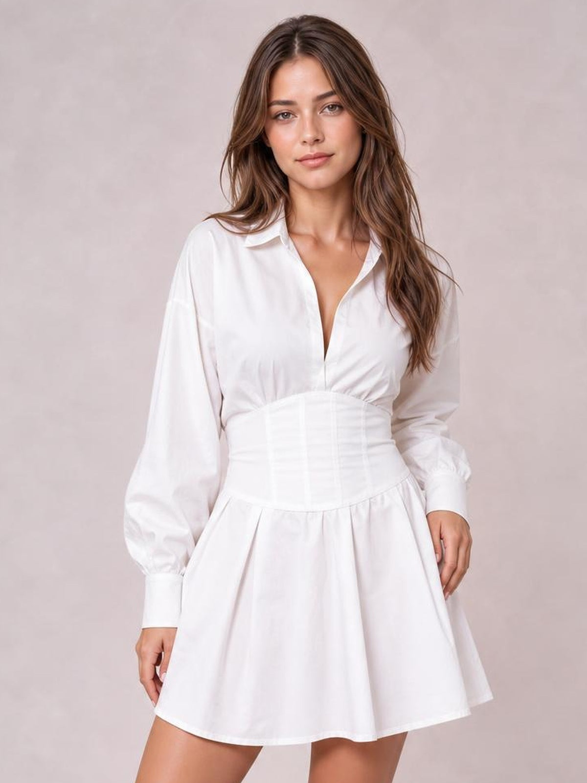 A model poses in a white collared neck mini dress with long lantern sleeves, ruched corset-style waist, button front, and flared skirt.