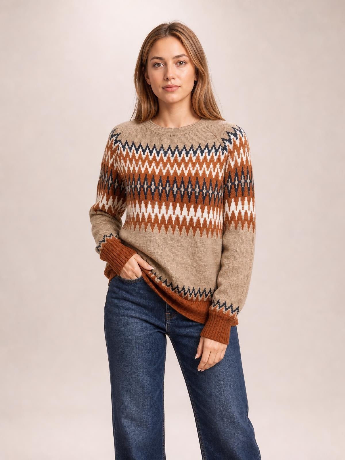 A model poses in a beige color block crew neck sweater with rust, cream, and navy geometric bands, relaxed long sleeves, and ribbed cuffs and hem.
