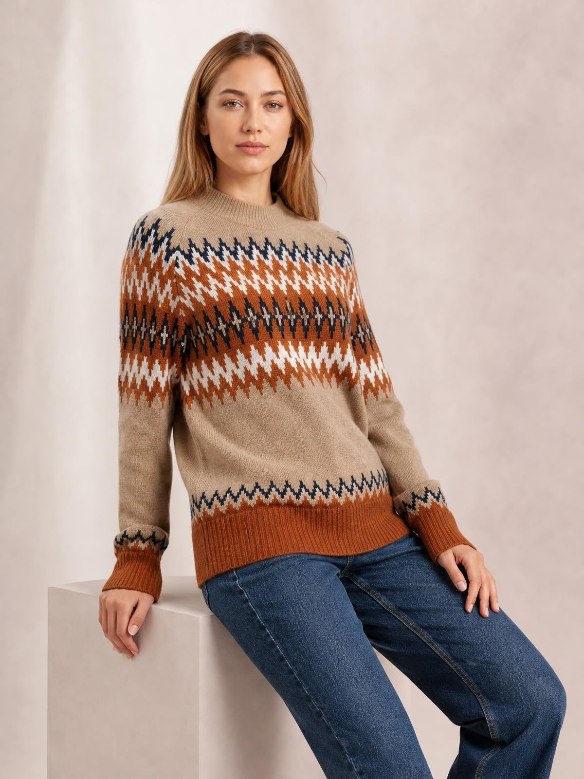 A model sits in a relaxed color block crew neck sweater with tan, rust, navy, and white geometric bands, long sleeves, ribbed cuffs, and hem.