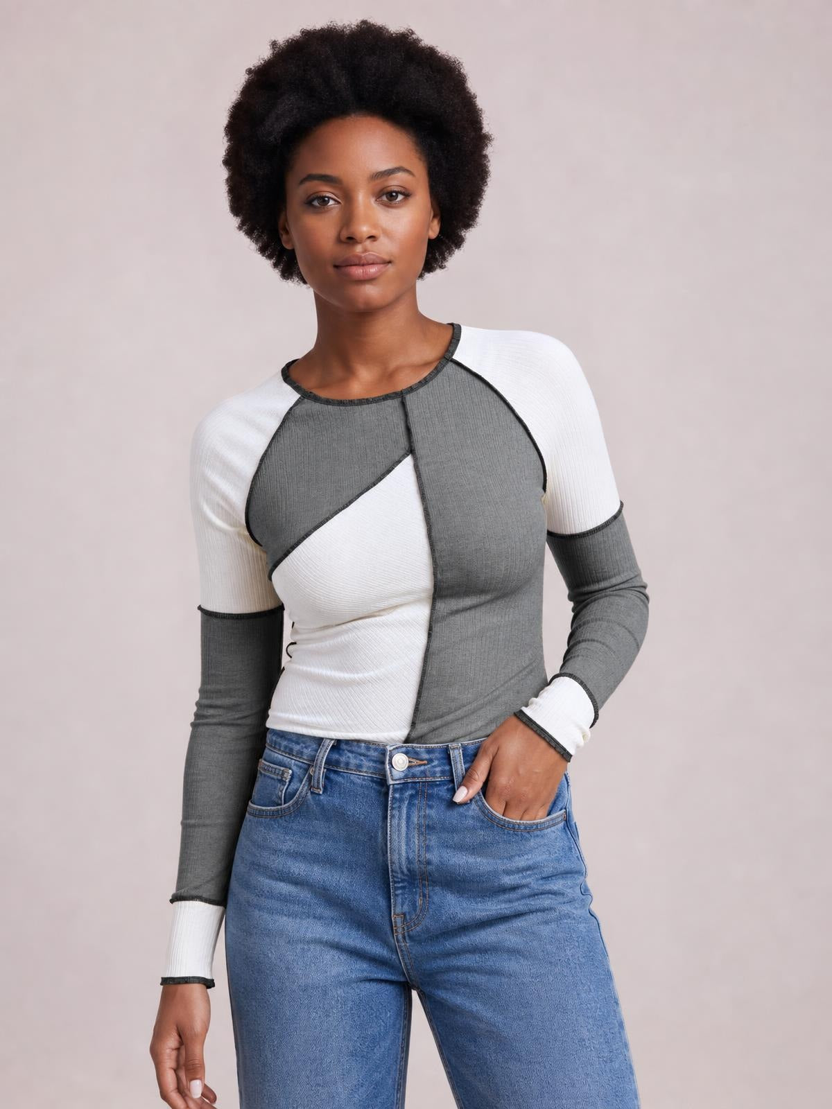 Model wearing a gray and white color block knit top with ribbed texture, exposed seams, round neck, raglan long sleeves, and a fitted silhouette.