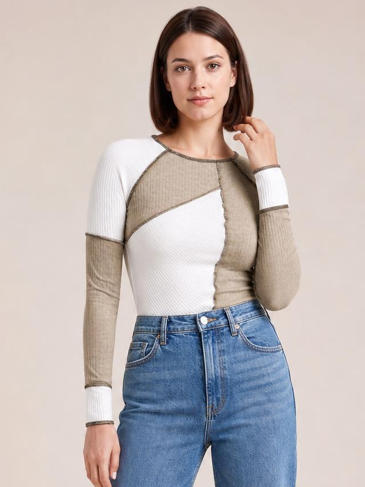 Model poses with one hand touching her hair, wearing a fitted color block ribbed knit top with exposed seams, round neck, and long raglan sleeves.