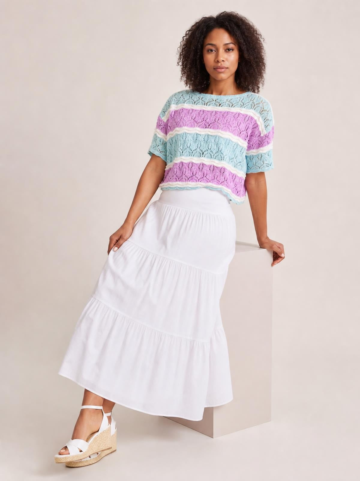 Model poses in a lightweight pastel color block openwork sweater with a loose silhouette, round neckline, and half sleeves.