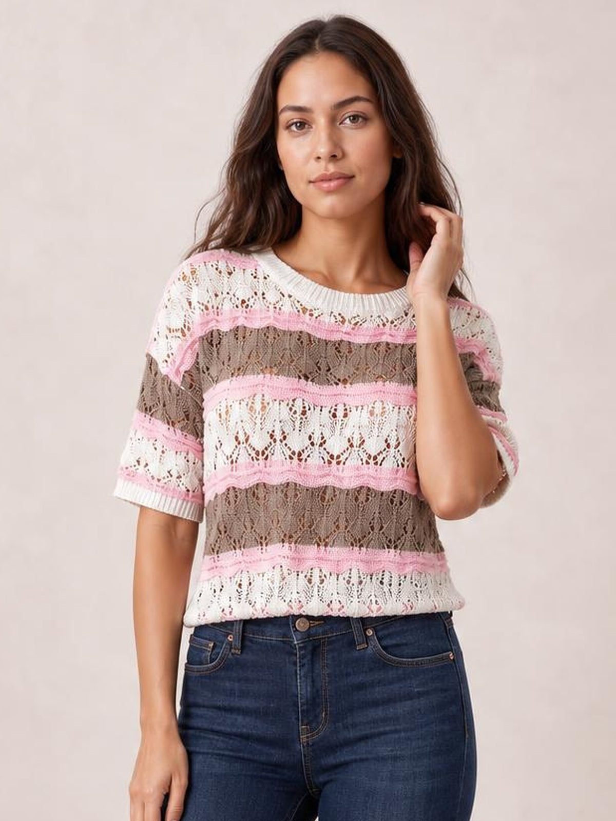 Model wearing a pink, white, and taupe color block openwork sweater with half sleeves, a ribbed crew neck, and a relaxed silhouette.