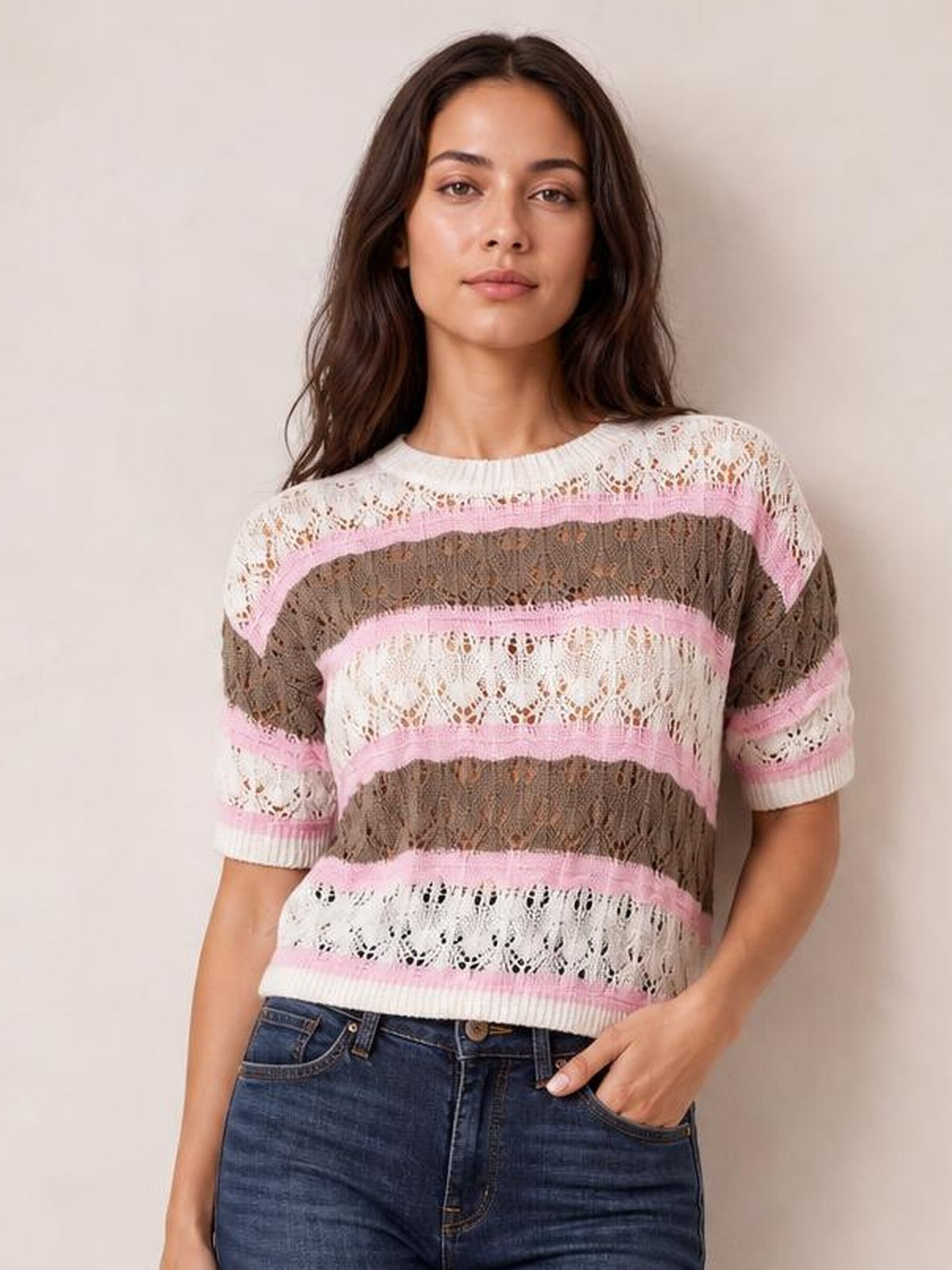 Model wearing a color block openwork sweater with pink, white, and taupe stripes, half sleeves, ribbed trim, and a relaxed silhouette.