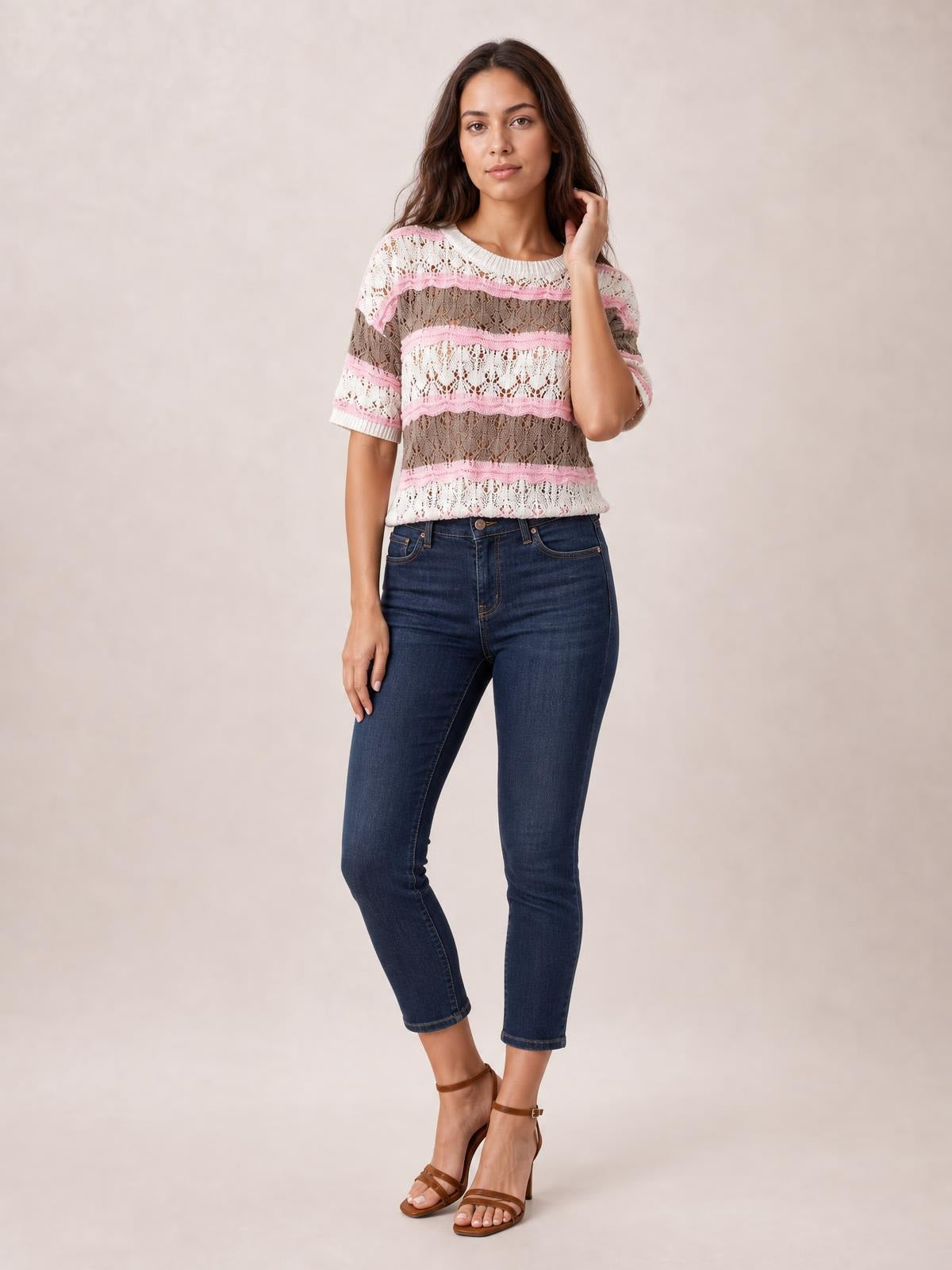 Model poses in a lightweight pink, white, and taupe color block openwork sweater with a crew neckline, half sleeves, and relaxed silhouette.