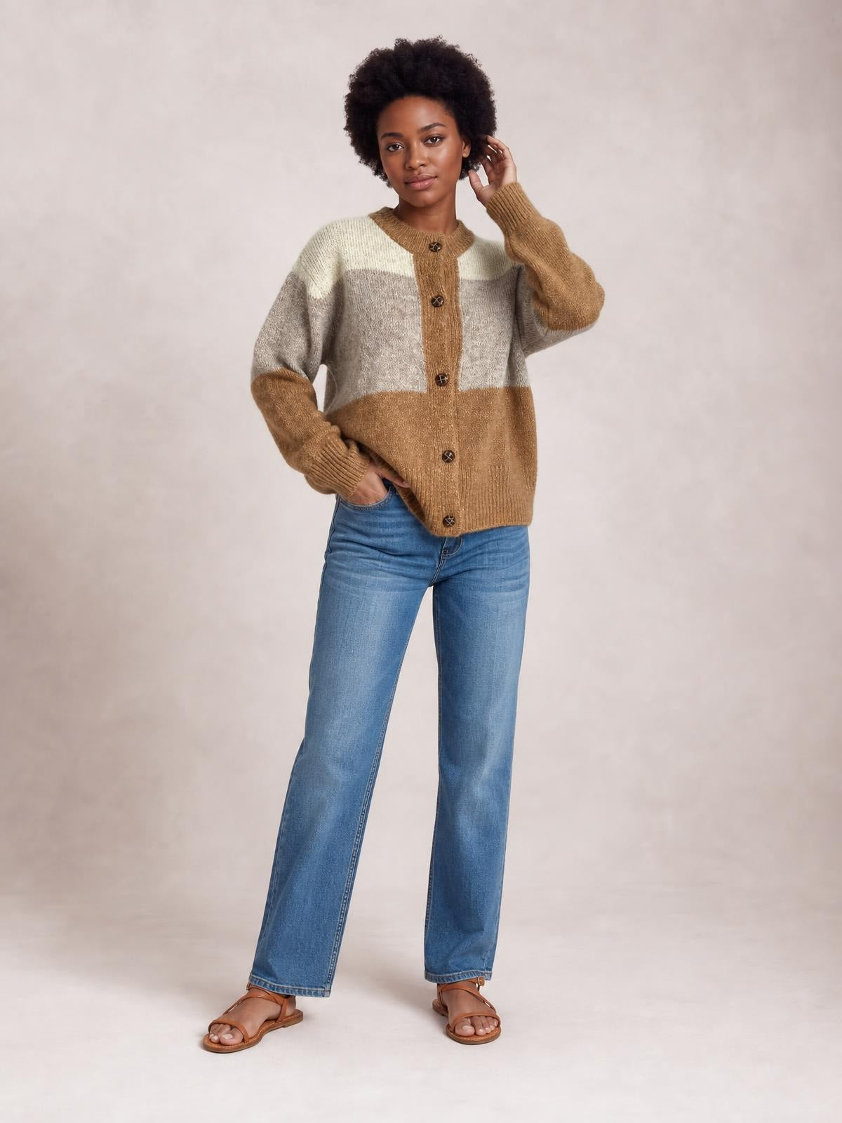 Model poses in a color-block round neck cardigan with button-up front, ribbed trim, long sleeves, and a relaxed hip-length silhouette in camel, gray, and cream.
