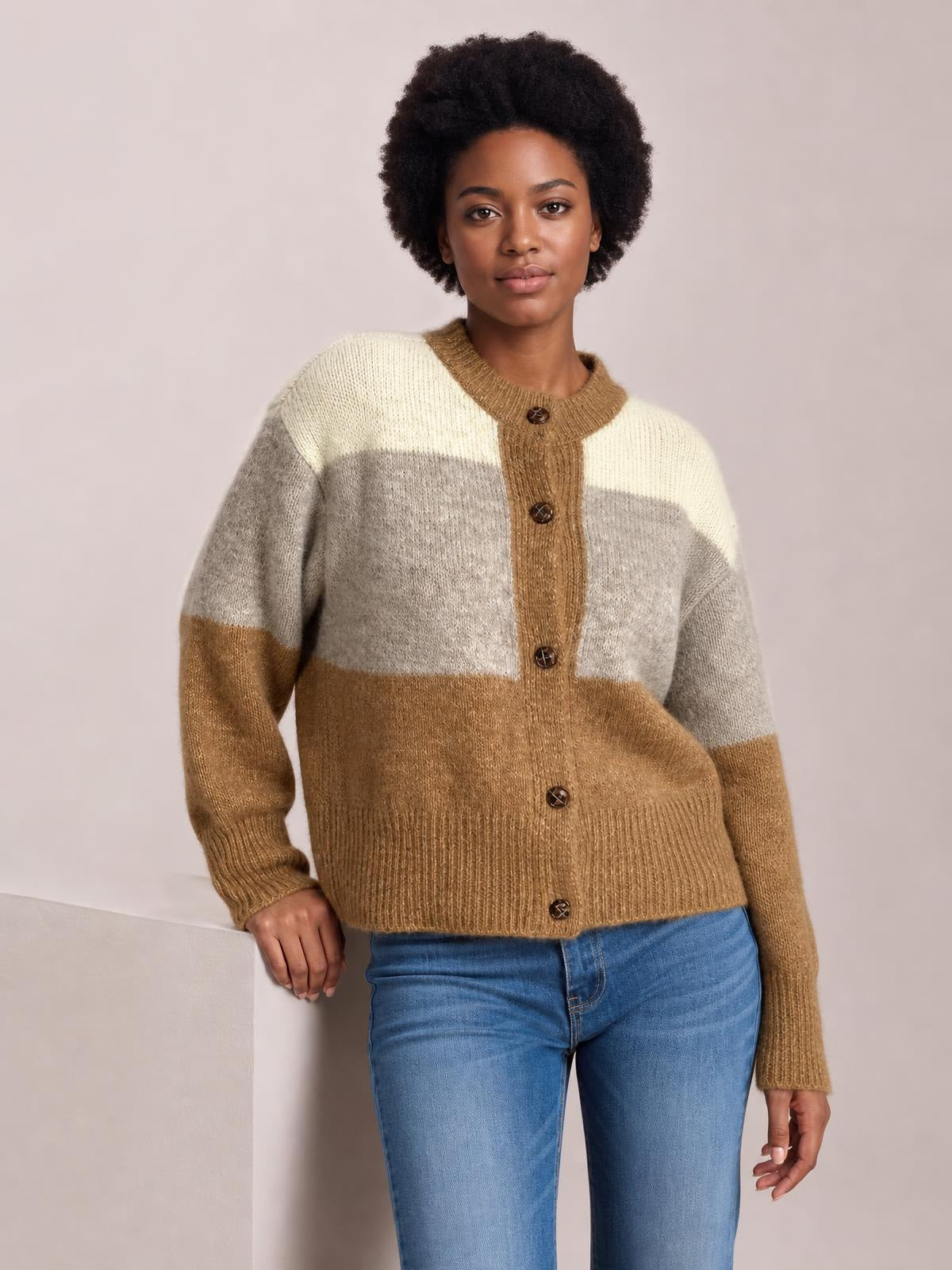 Model wearing a color block round neck button-up cardigan with cream, gray, and camel panels, long sleeves, ribbed trim, and a relaxed silhouette.