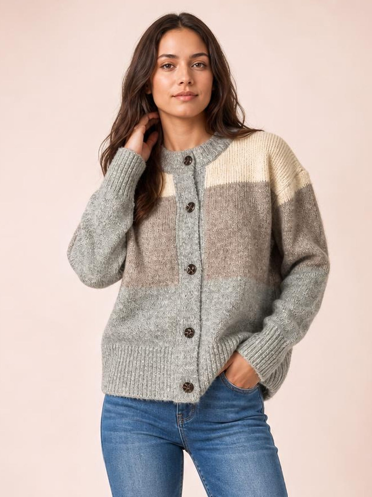 Model poses in a gray, taupe, and cream color block round neck button-up cardigan with long sleeves, ribbed trim, and a relaxed silhouette.
