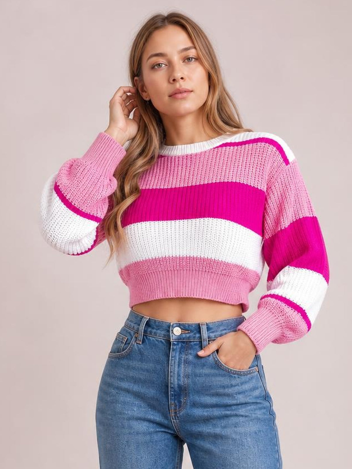 Model touching her hair while wearing a pink, magenta, and white color block cropped sweater with a round neck, ribbed hem, and long sleeves.