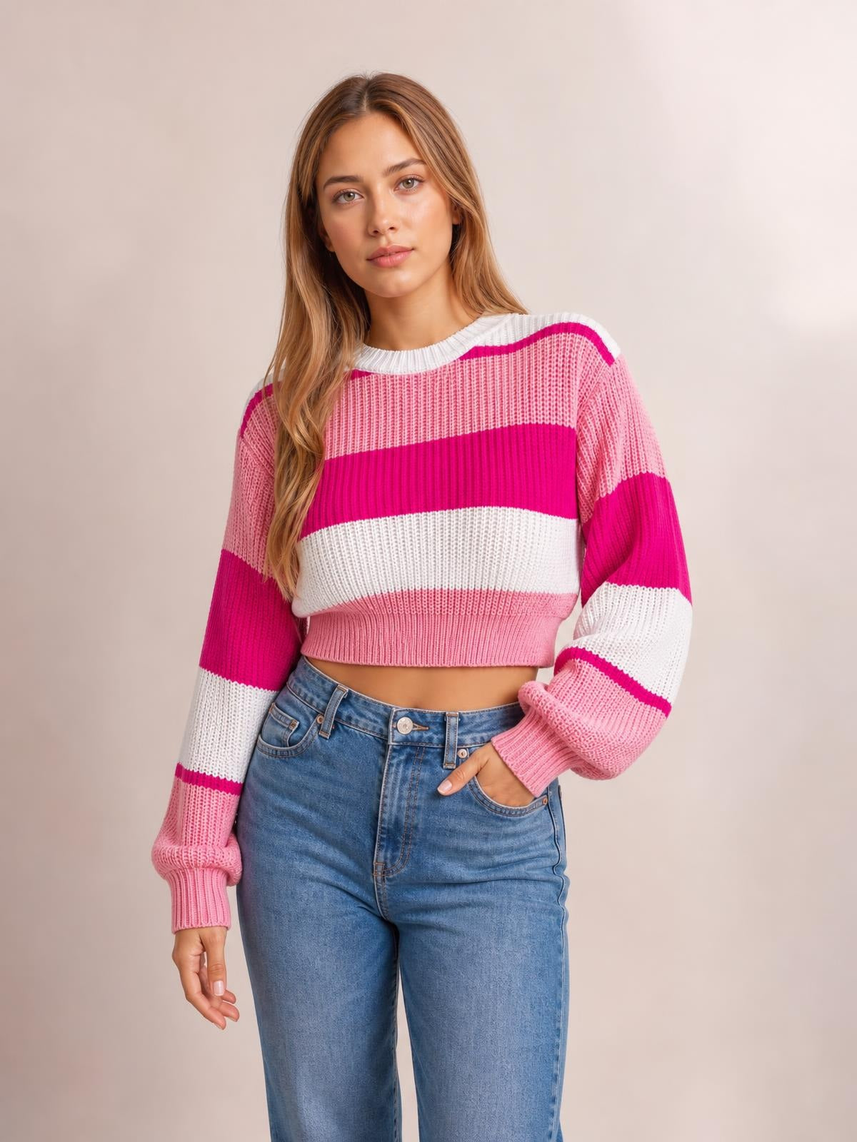 Model wears a pink and white color block cropped sweater with a round neck, ribbed knit construction, long sleeves, and a relaxed silhouette.