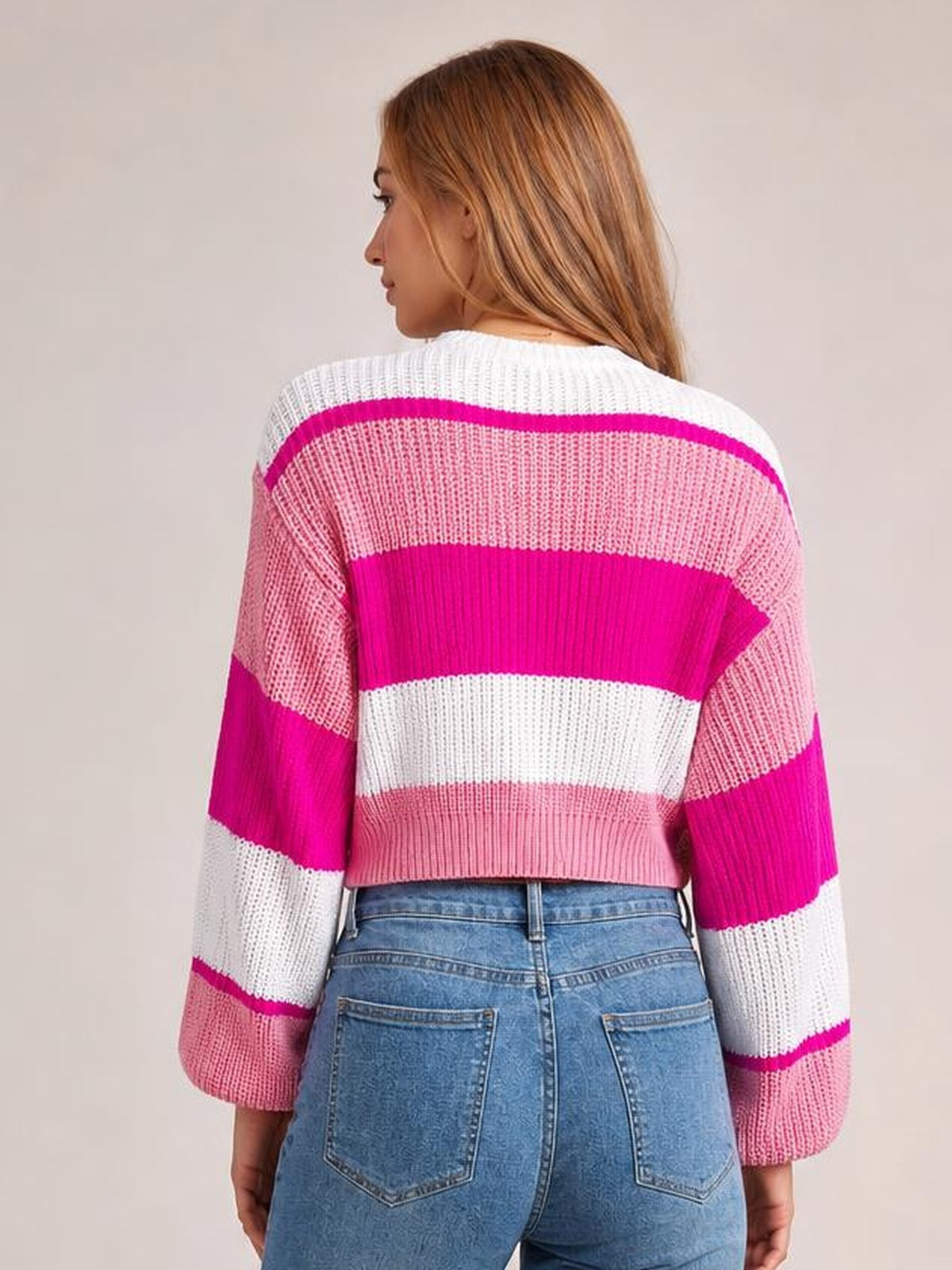 Model shown from the back wearing a pink and white color-block cropped sweater with a round neck, ribbed knit construction, and long sleeves.