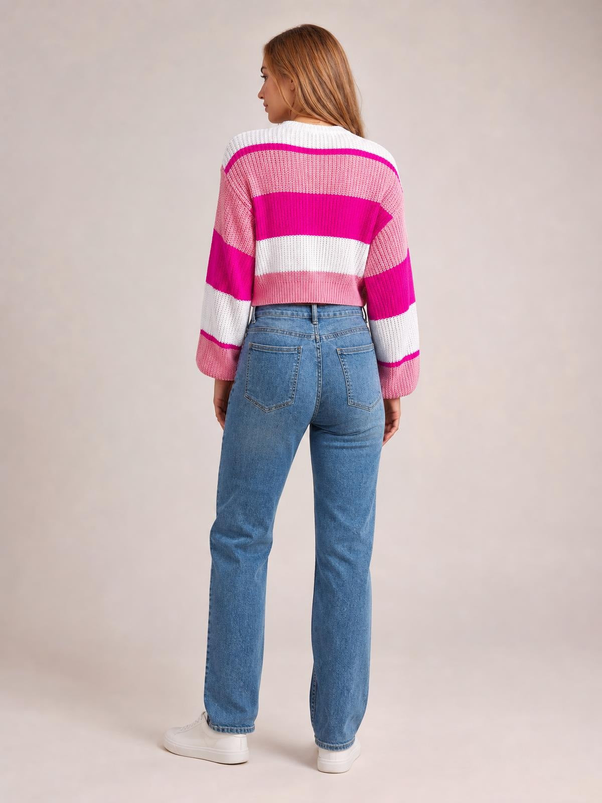 Model shown from the back wearing a pink, magenta, and white color block round neck cropped sweater with long sleeves and a ribbed hem.