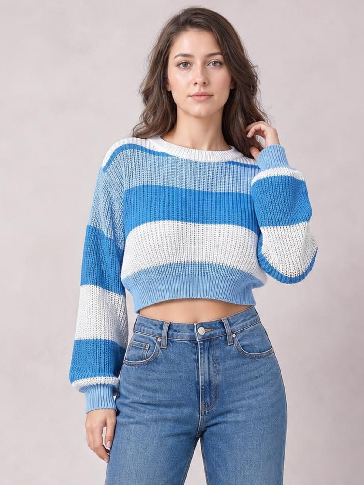 Model poses in a blue-and-white color block cropped sweater with a round neck, ribbed hem and cuffs, and relaxed long sleeves.