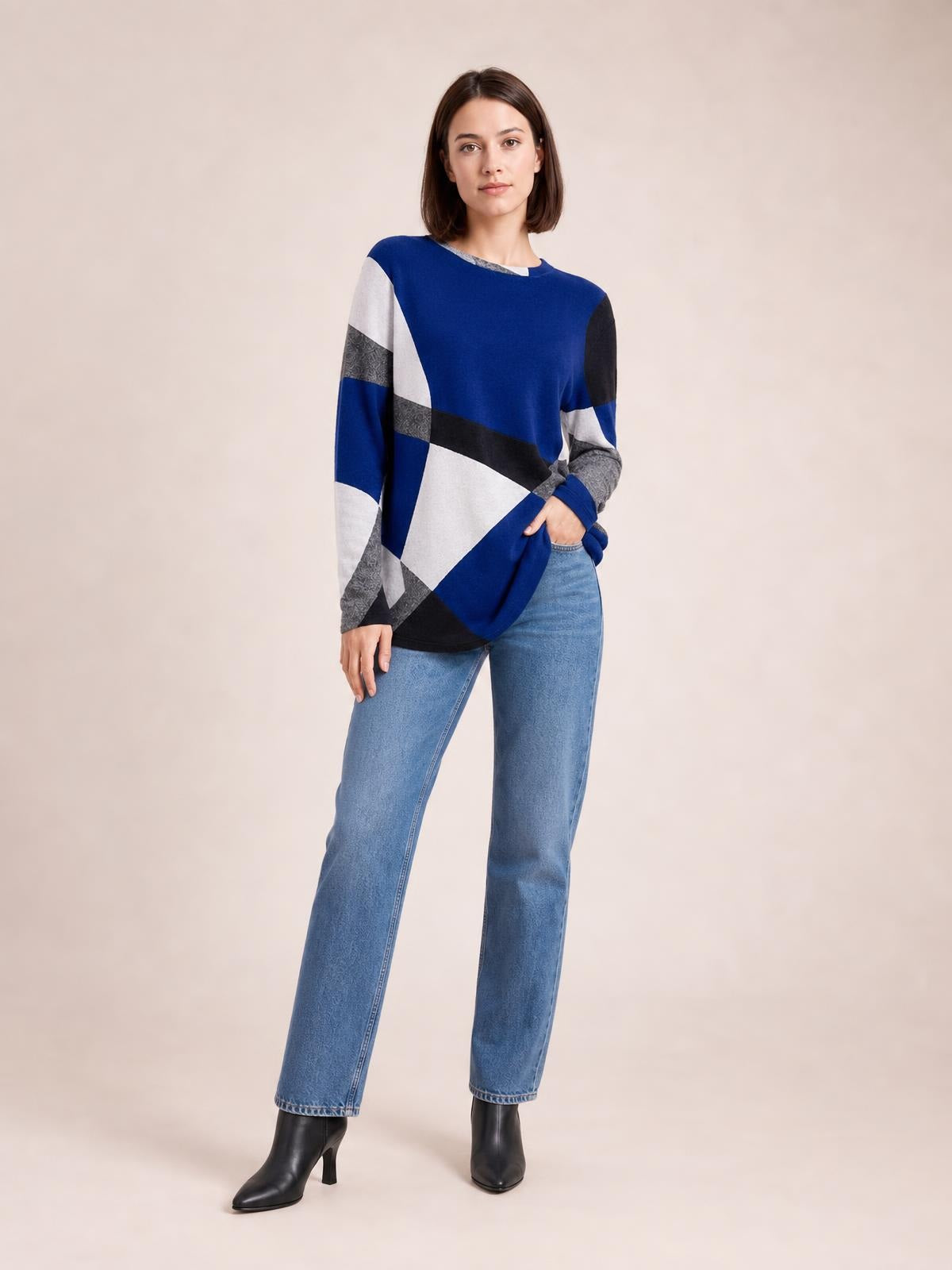 Model standing in a color block round neck T-shirt with blue, white, gray, and black panels, long sleeves, and a relaxed straight silhouette.