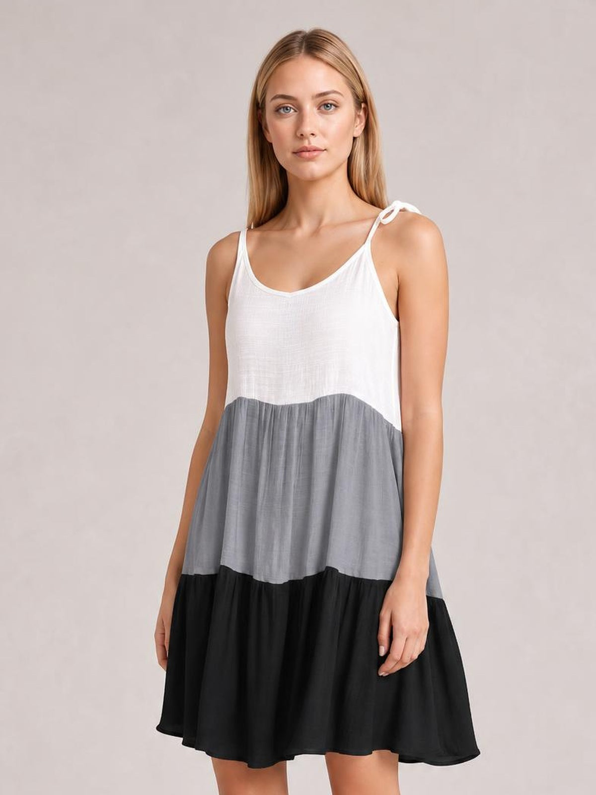 Model wearing a semi-sheer color block spaghetti strap cover-up dress with white, gray, and black tiers, a loose A-line silhouette, and bow-tie shoulder straps.