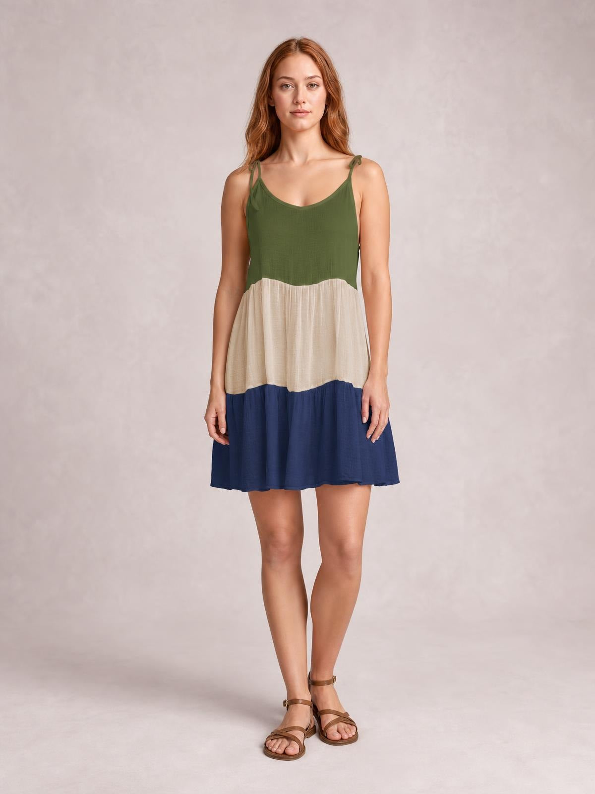 A model stands with arms relaxed in a semi-sheer color-block spaghetti strap cover-up dress with green, ivory, and navy tiers and a loose short silhouette.