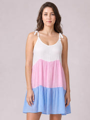 Model wears a semi-sheer color block cover-up dress with white spaghetti straps, a pink tier, and a flared light blue mini-length skirt.