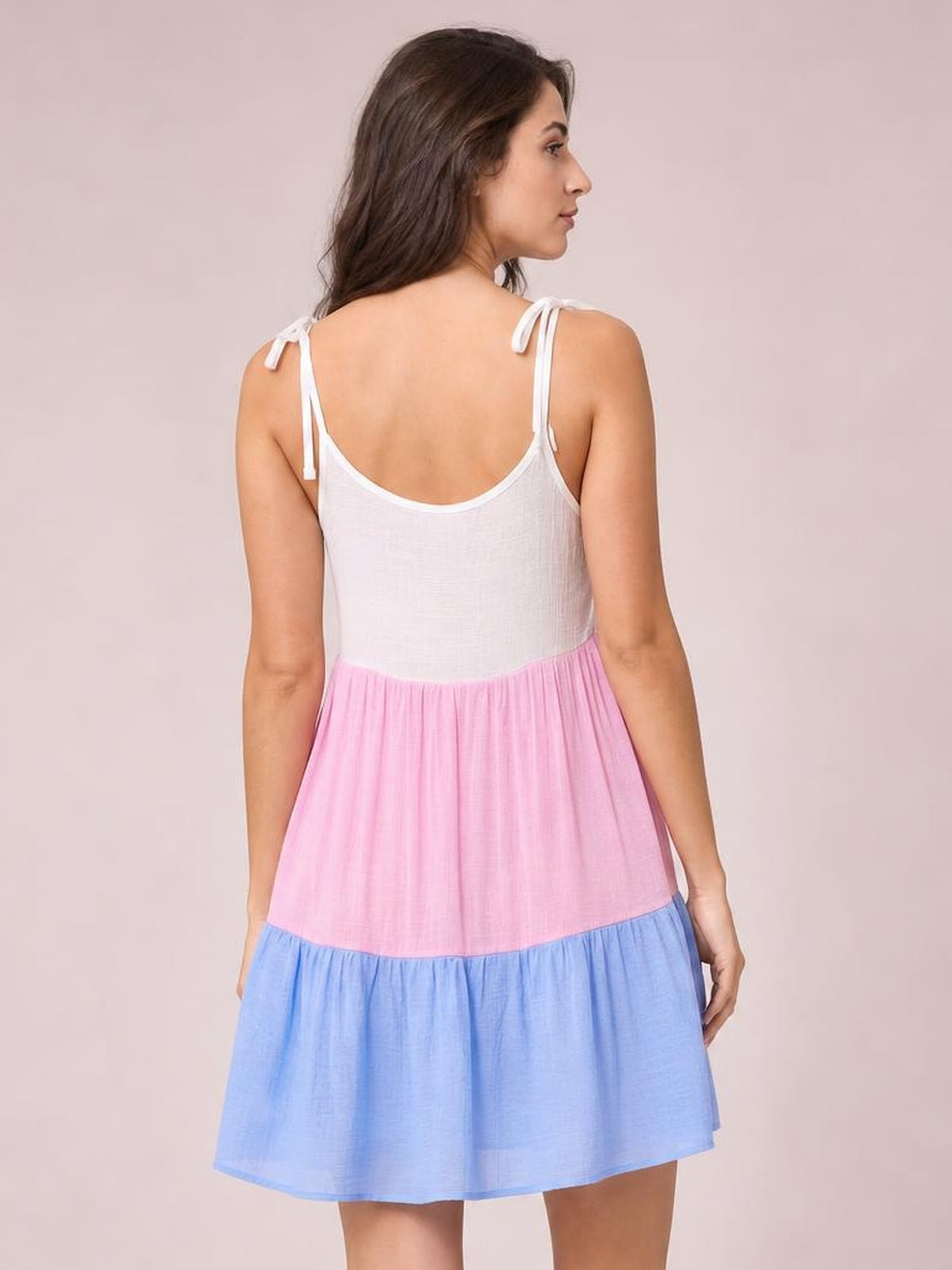 Model shown from behind wearing a semi-sheer color block spaghetti strap cover-up dress with white, pink, and blue tiered sections and a relaxed silhouette.