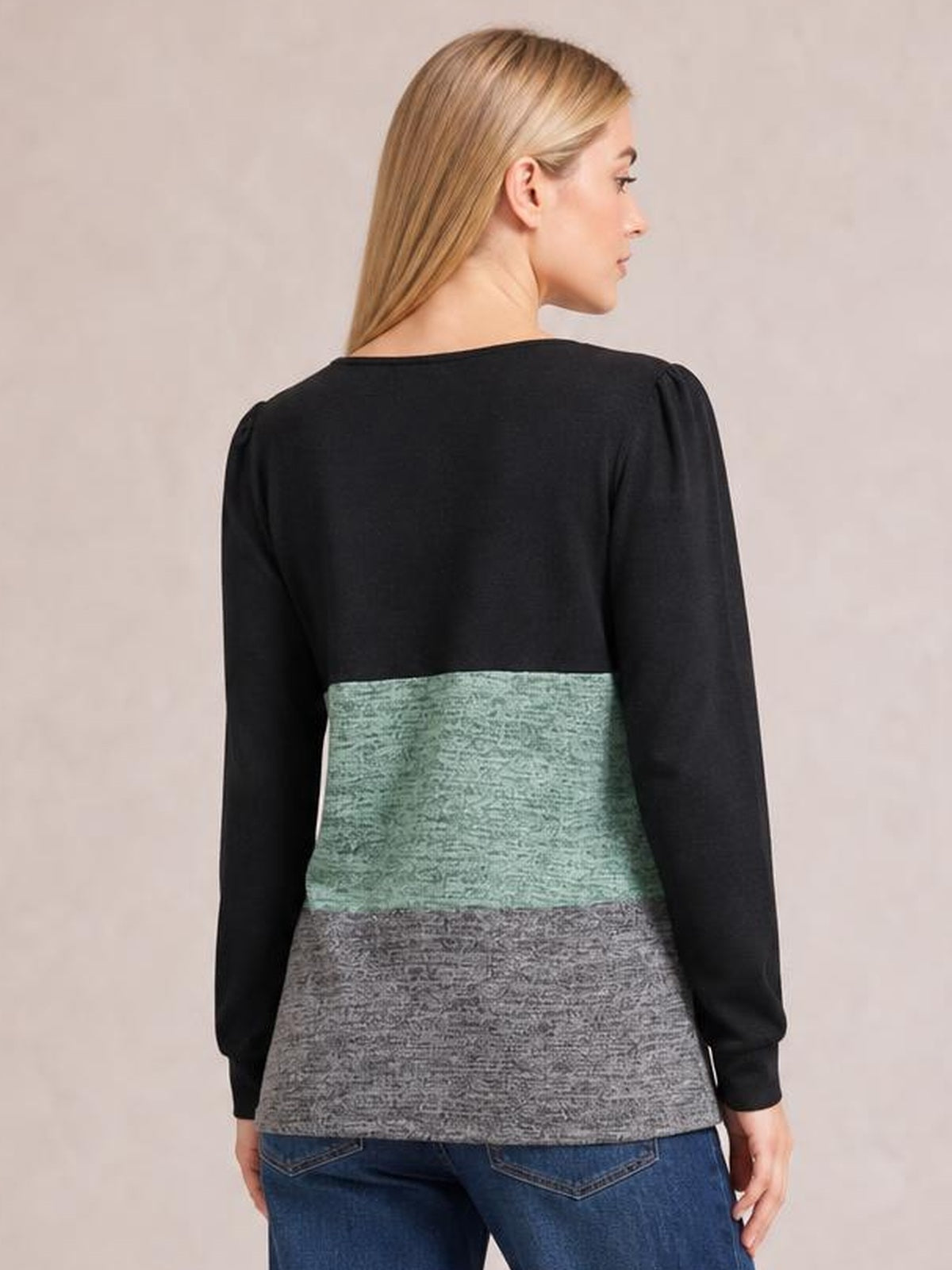 Model shown from behind wearing a color block long sleeve T-shirt with black sleeves, mint green and gray panels, a relaxed straight silhouette, and cuffed wrists.