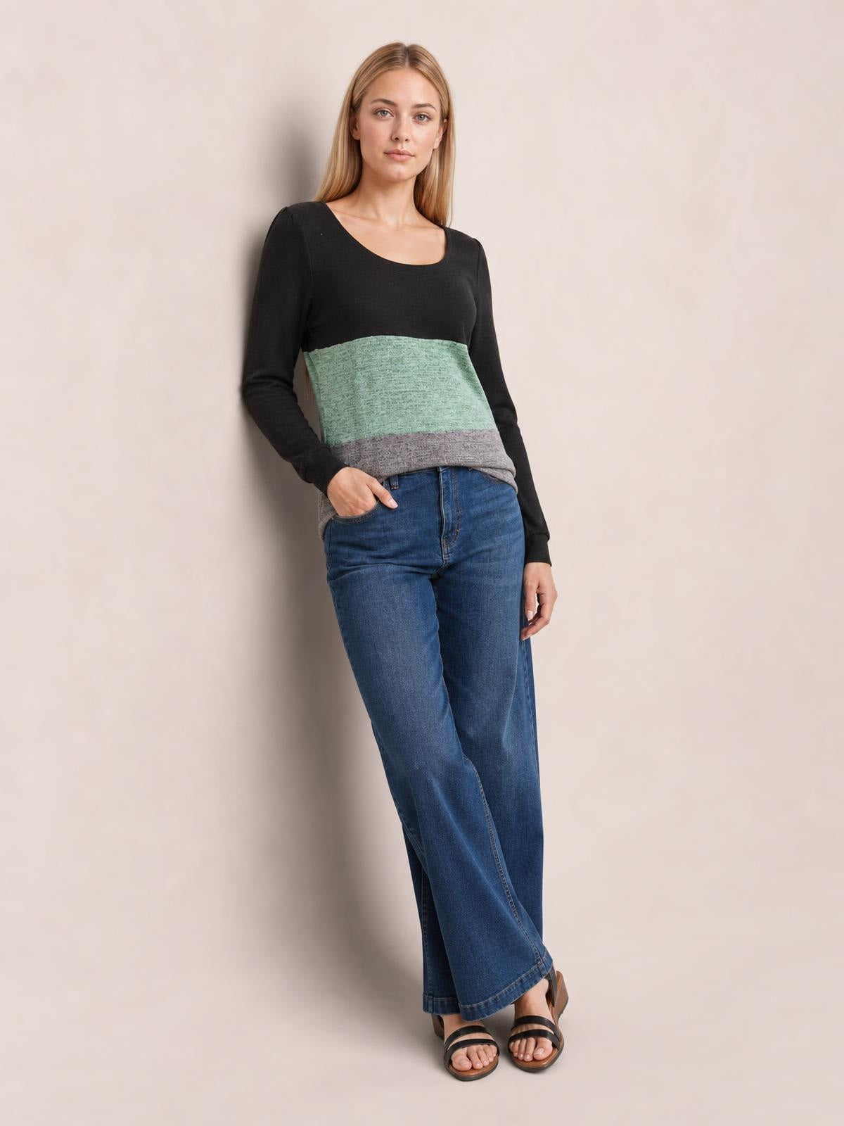 A model wears a color block square neck long sleeve T-shirt with black, mint green, and gray panels in a relaxed silhouette, posing with one hand in her jeans pocket.