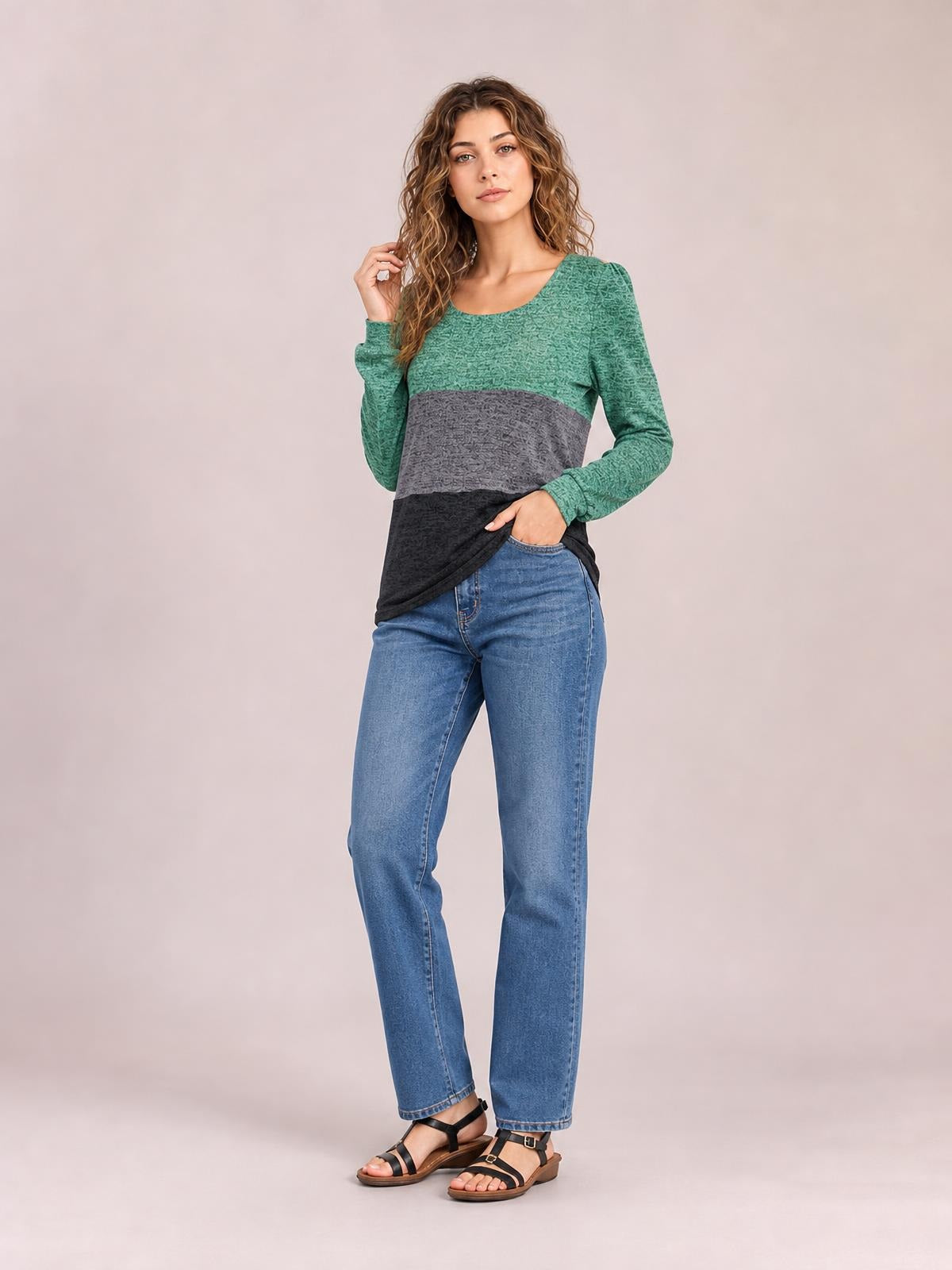 Model wears a green, gray, and black color block square neck long sleeve T-shirt with a relaxed silhouette, posing with one hand in her jeans pocket.