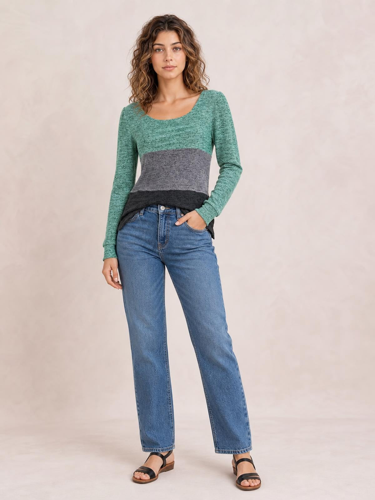 A model stands with one hand in her jeans pocket wearing a fitted color block long sleeve T-shirt with a square neckline and green, gray, and black panels.
