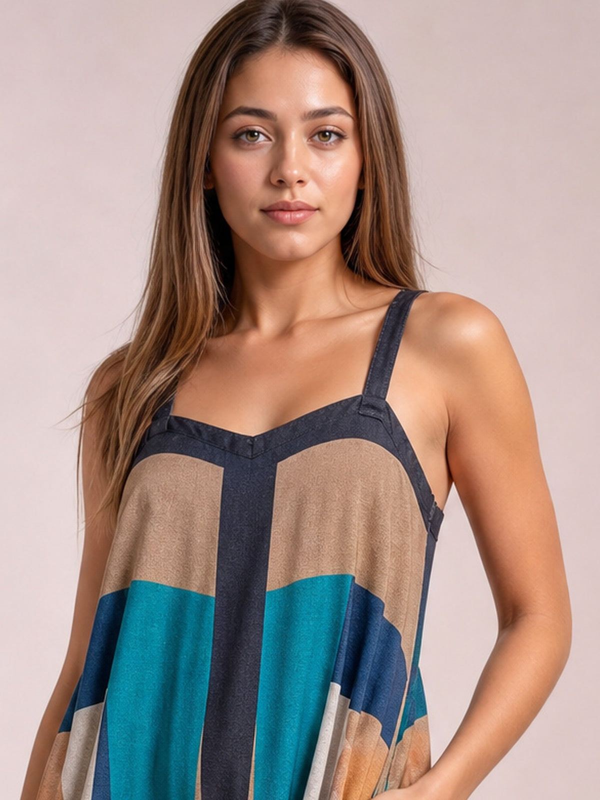 Model wearing a color-block dress with a square neckline, wide straps, flowing silhouette, and bold brown, teal, navy, cream, and golden panels.