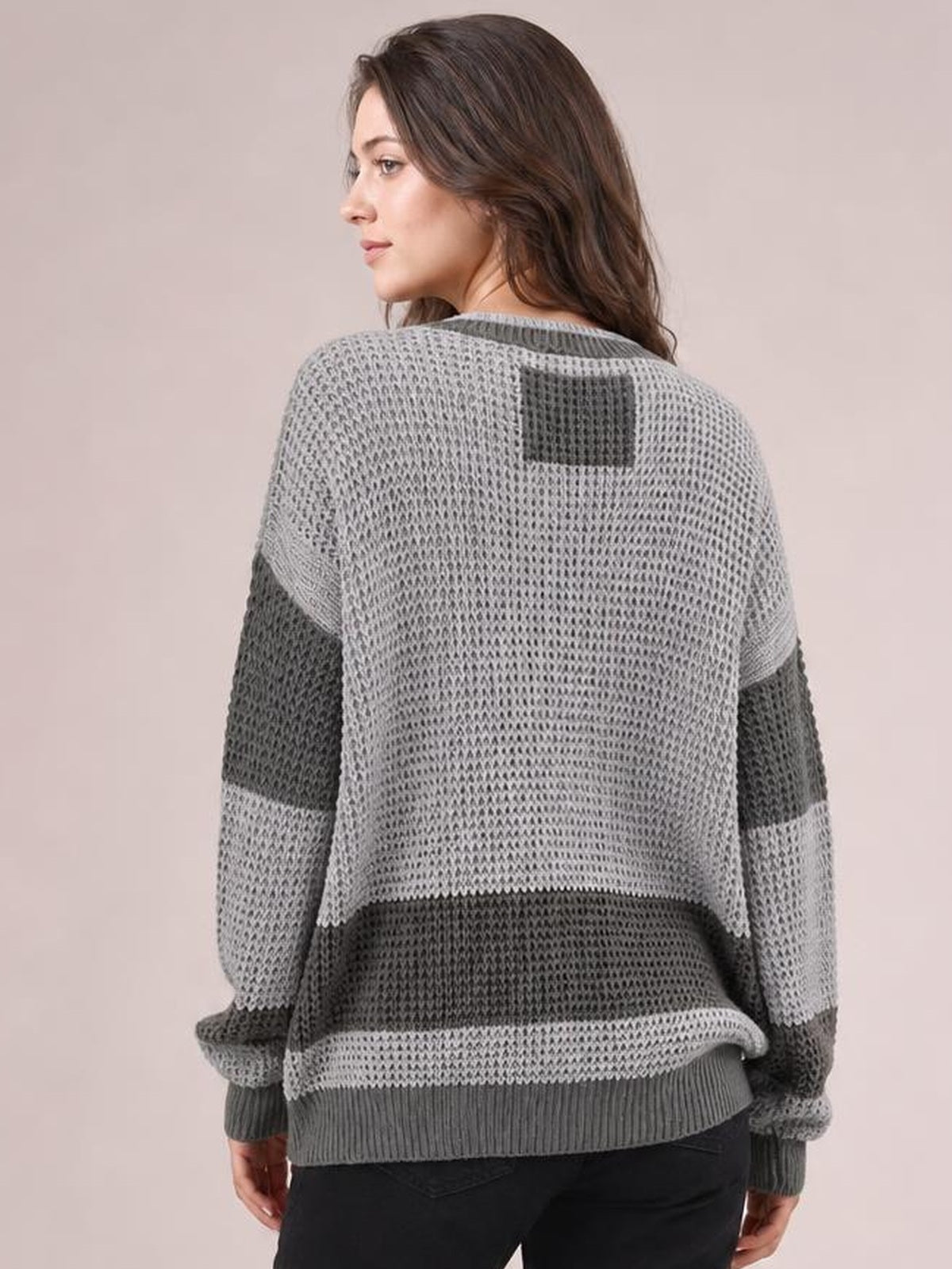 Model shown from the back wearing a relaxed gray color block cardigan with waffle-knit texture, contrasting panels, long sleeves, and ribbed cuffs and hem.