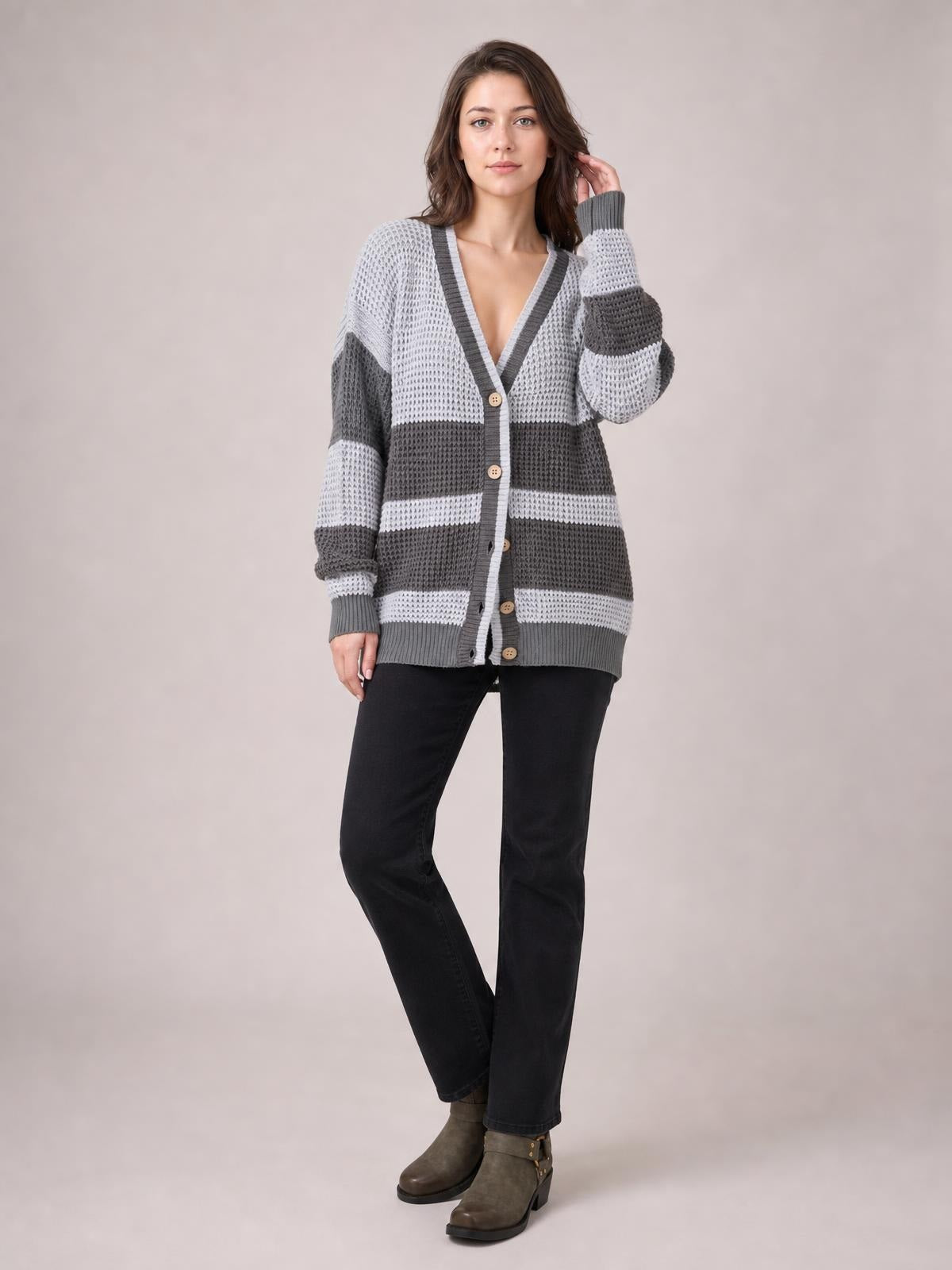 Model poses with one hand in her hair wearing a gray and white color block V-neck cardigan with waffle-knit texture, button front, and relaxed longline fit.