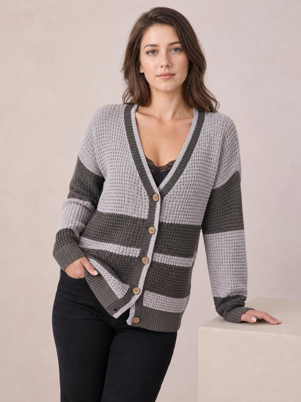 Model wearing a gray color block V-neck cardigan with waffle-knit texture, striped panels, button front, ribbed trim, and a relaxed silhouette.