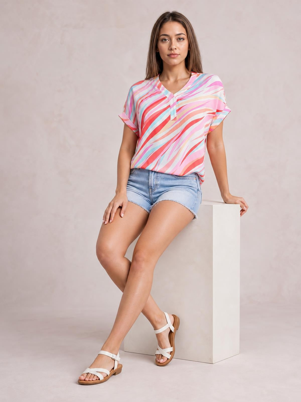 A seated model wears a flowing multicolor Color Block V-Neck Half Sleeve Blouse with bold abstract stripes and a relaxed silhouette.