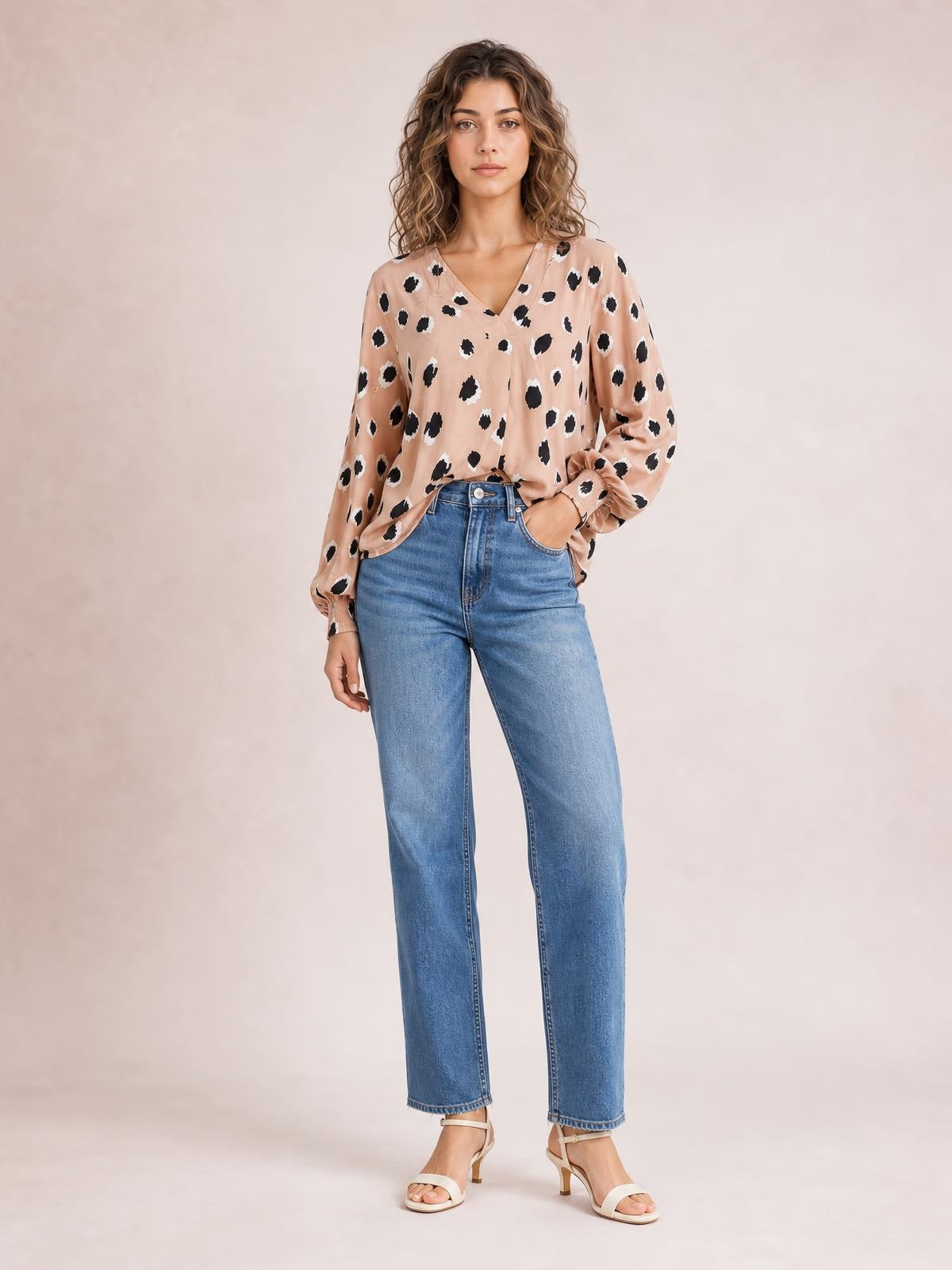 Model wears a peach V-neck long-sleeve blouse with contrasting black animal print, relaxed silhouette, button front, and gathered cuffs.