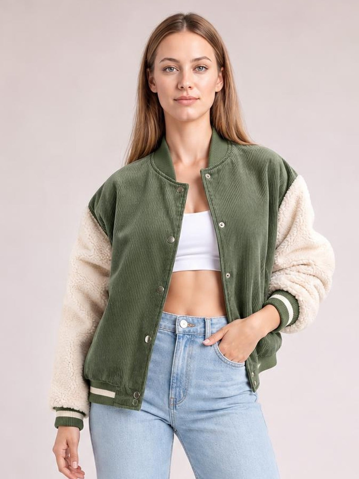A woman poses front-facing in an olive green contrast baseball collar jacket with a snap-down front, cream textured long sleeves, striped cuffs, and a relaxed fit.