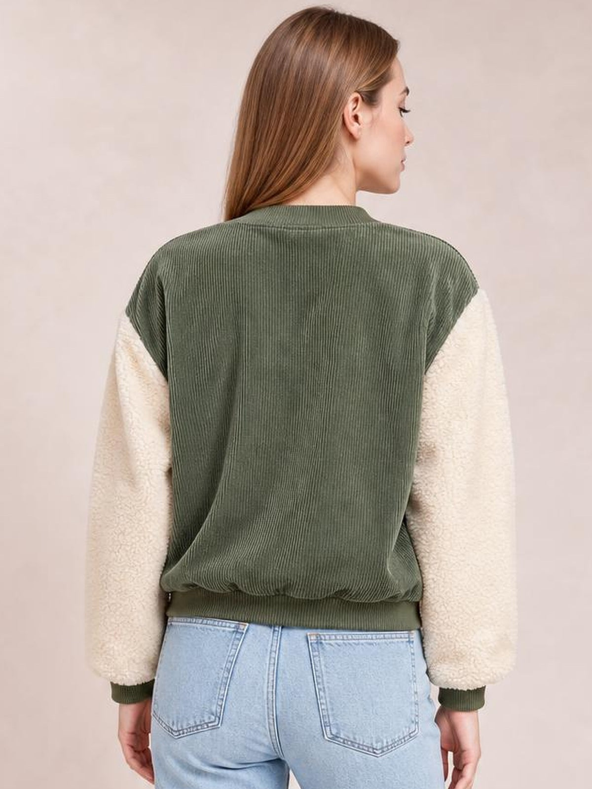 Model viewed from the back wears a relaxed olive green jacket with a ribbed baseball collar, contrasting cream long sleeves, ribbed cuffs, and hem.