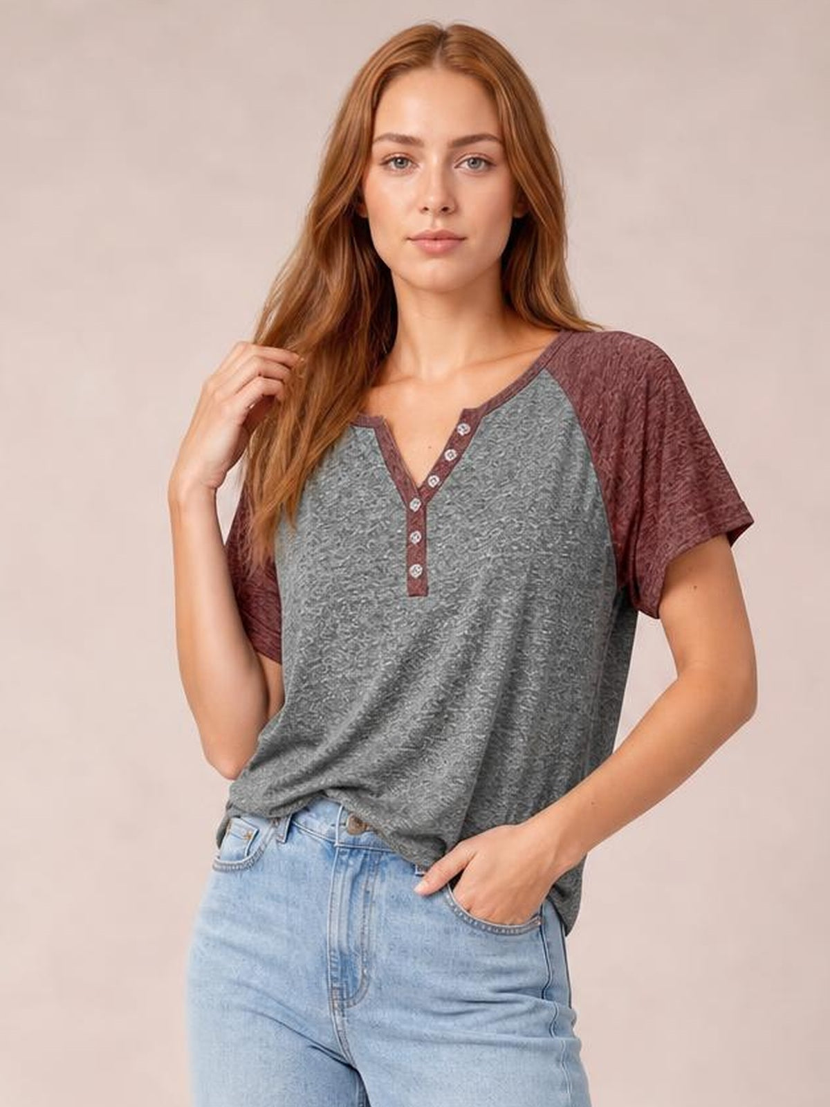 A model poses in a gray contrast notched short sleeve T-shirt with burgundy sleeves, trim, and button placket in a relaxed silhouette.