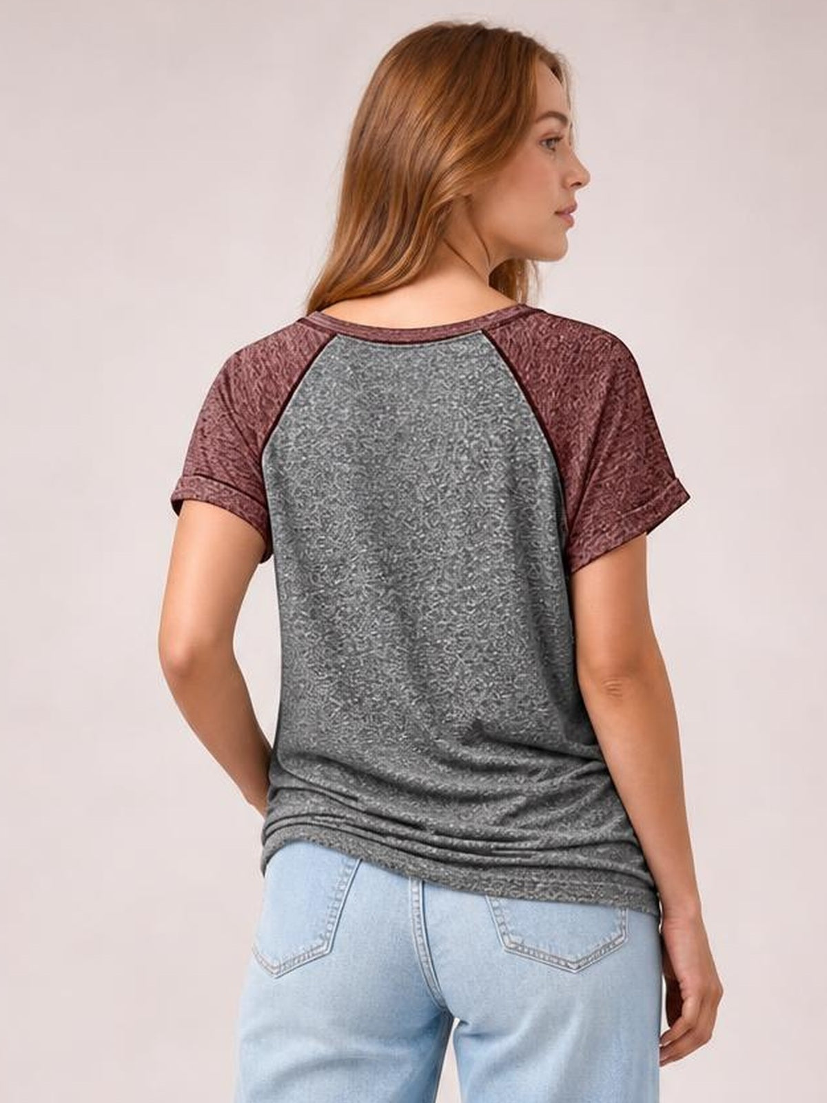 Model shown from behind in a gray contrast short sleeve T-shirt with burgundy raglan-style sleeves, a relaxed silhouette, and a slightly curved hem.