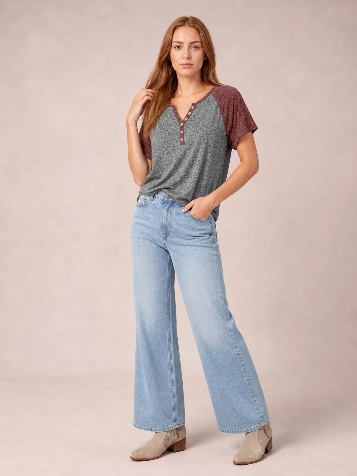 A model poses in a relaxed contrast notched short-sleeve T-shirt with a gray body, burgundy sleeves and trim, and a decorative button placket.