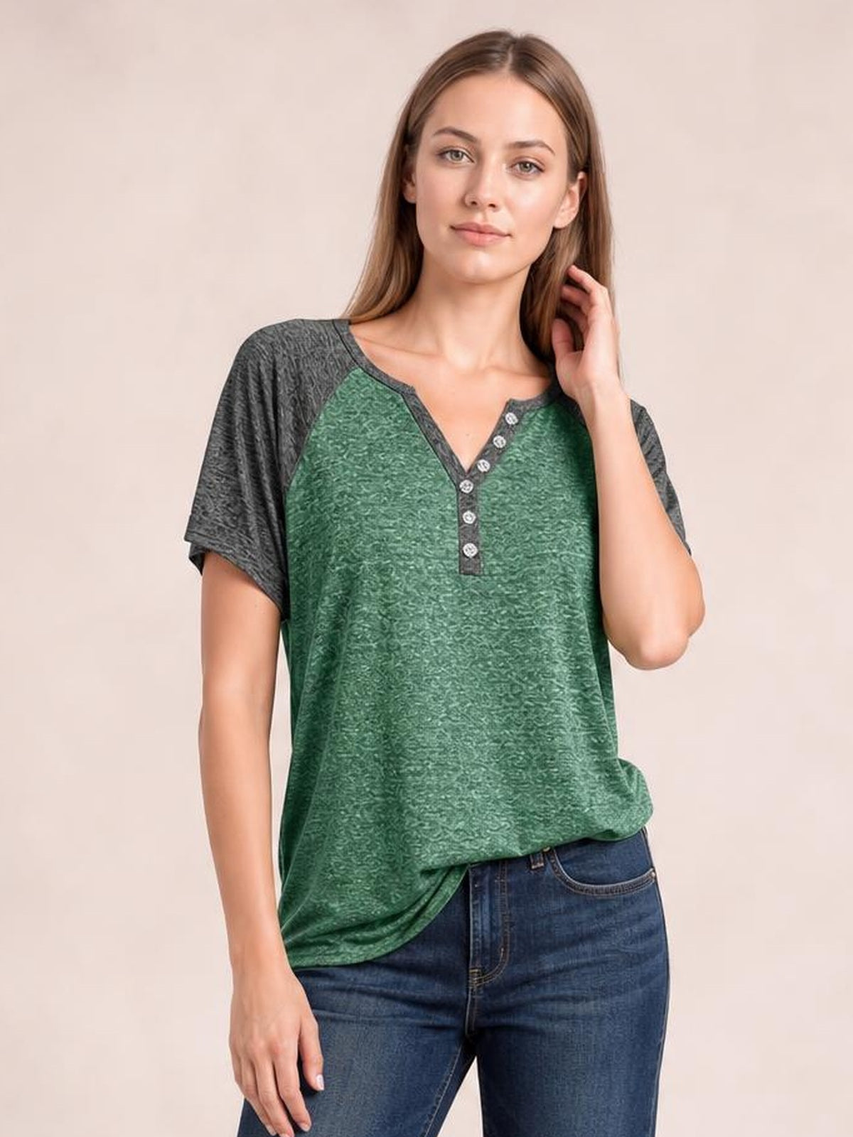 Model poses in a green contrast notched short sleeve T-shirt with charcoal sleeves, a relaxed silhouette, and decorative button placket.