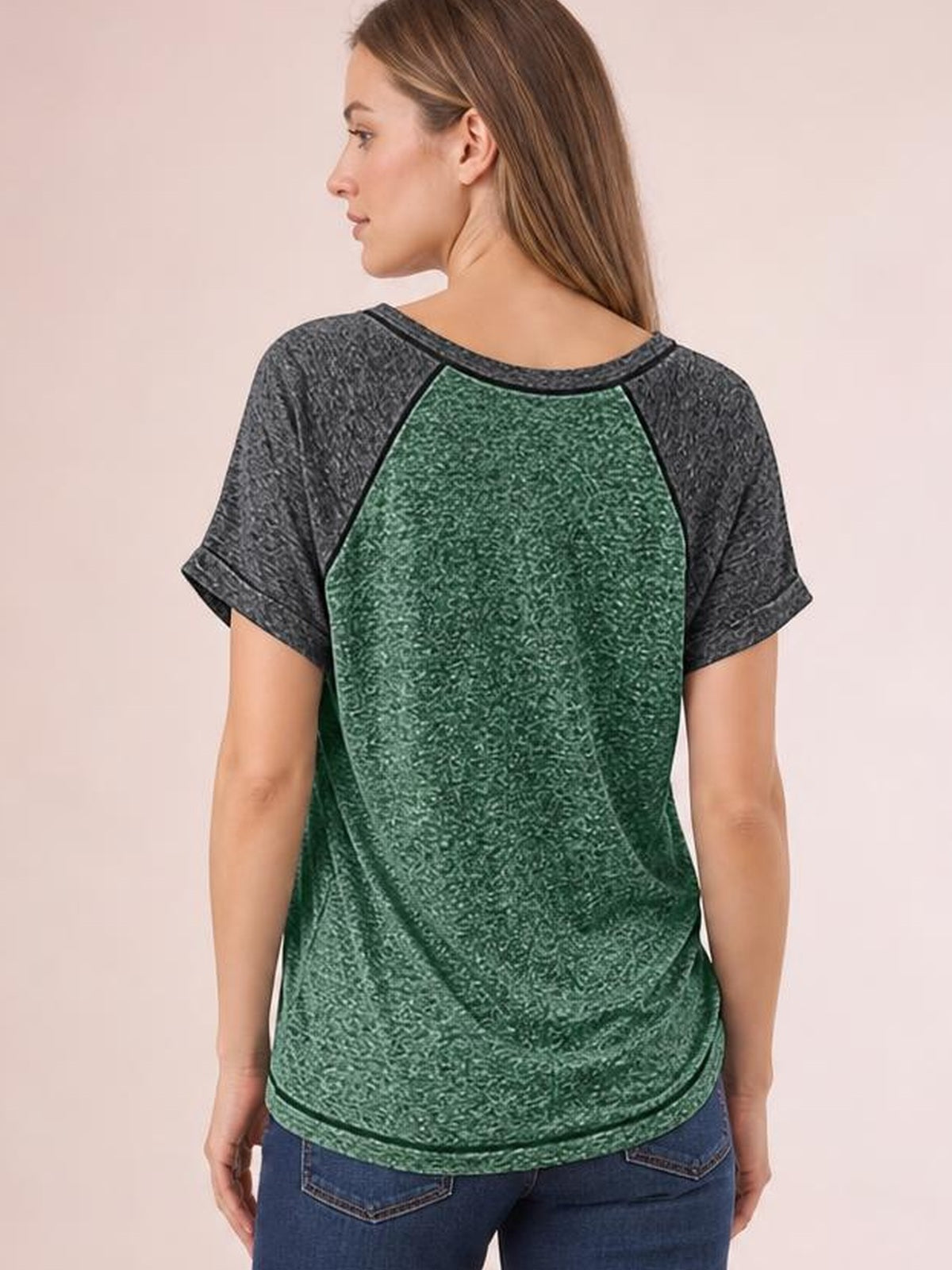 A woman models the back of a green contrast short sleeve T-shirt with charcoal sleeves, dark trim, a relaxed silhouette, and rounded hem.