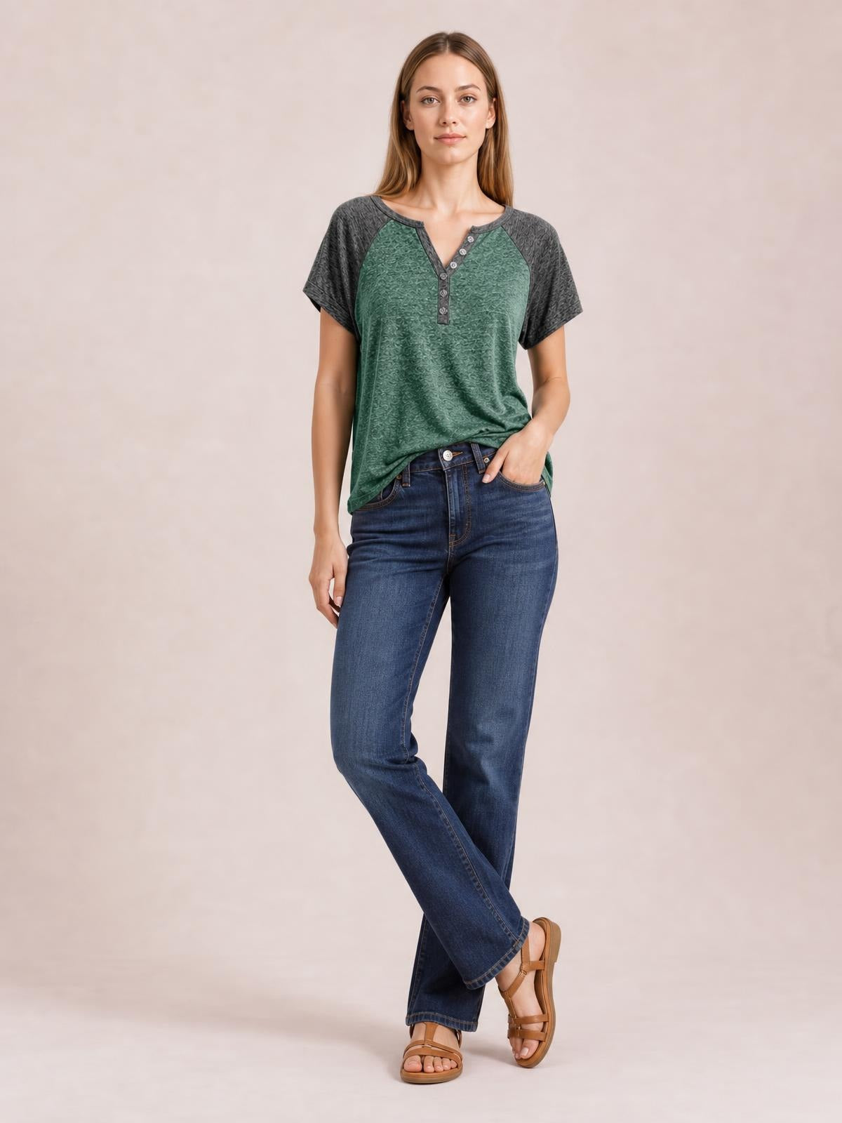 Model poses in a green contrast notched short sleeve T-shirt with charcoal raglan sleeves, decorative button placket, and a relaxed silhouette.