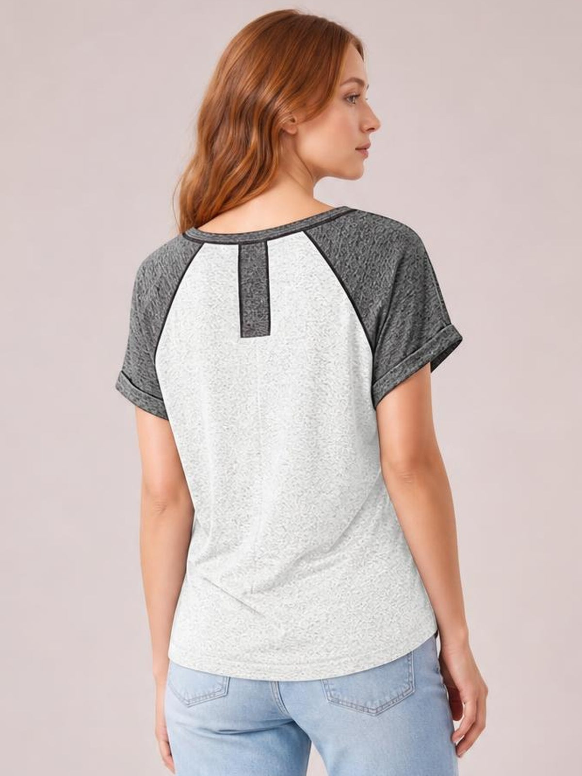A model poses in a relaxed contrast notched short-sleeve T-shirt with a light gray body, dark gray sleeves and trim, and a curved hem.