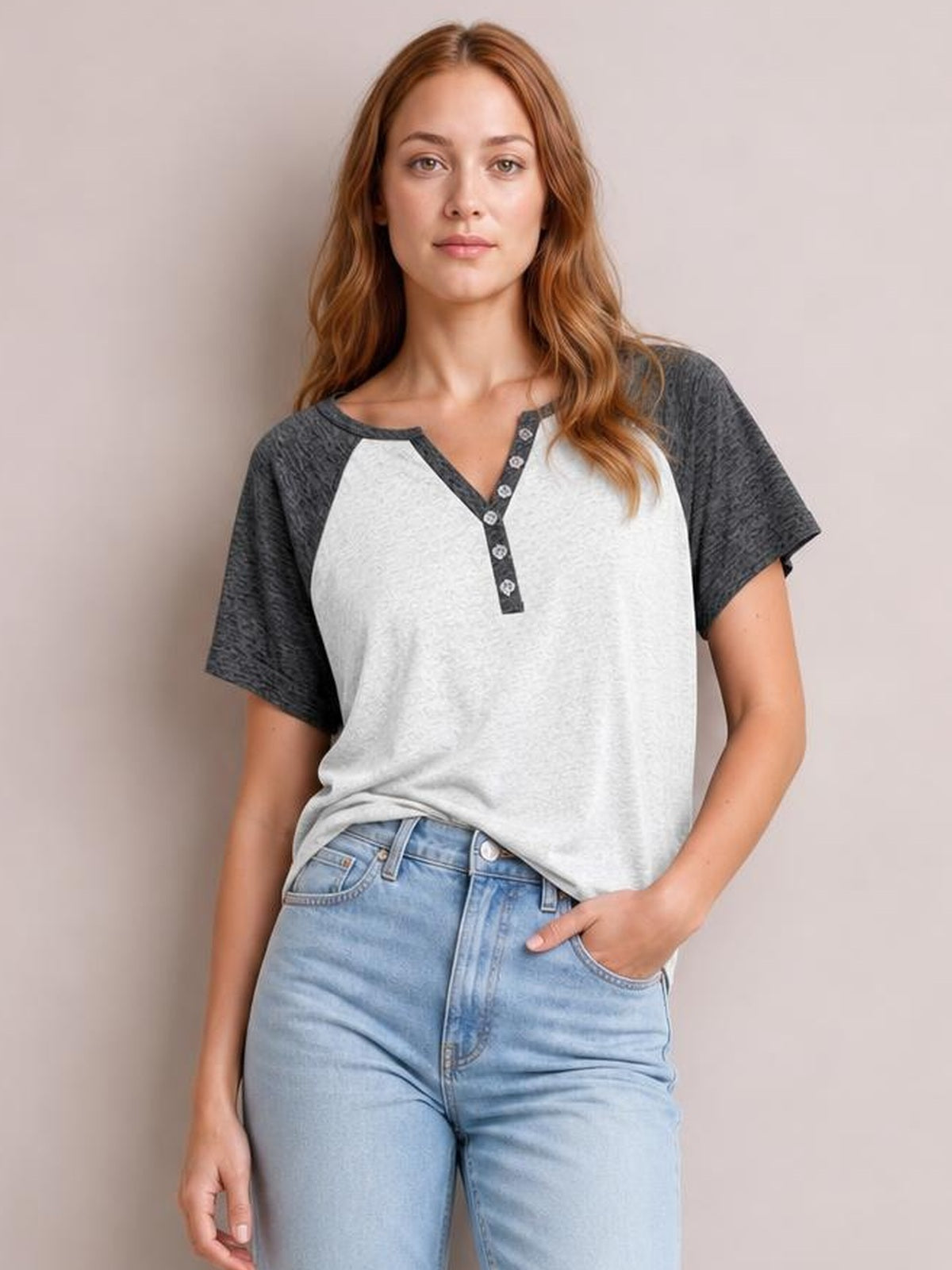 A woman stands in a contrast notched short sleeve T-shirt with a white body, charcoal sleeves, decorative button placket, and relaxed silhouette.