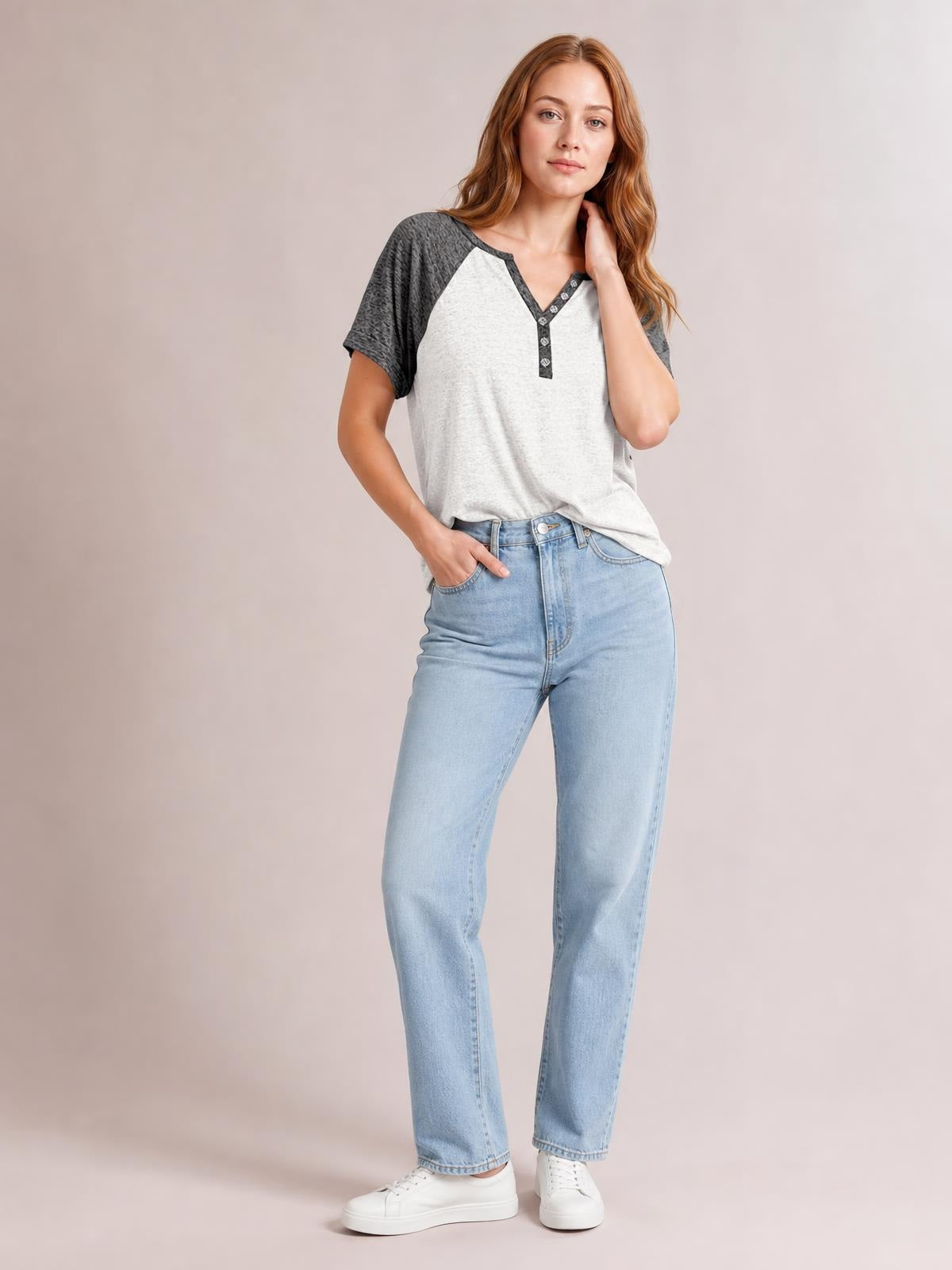 Model wears a light gray contrast notched short sleeve T-shirt with dark charcoal raglan sleeves, a buttoned V-neck placket, and a relaxed silhouette.