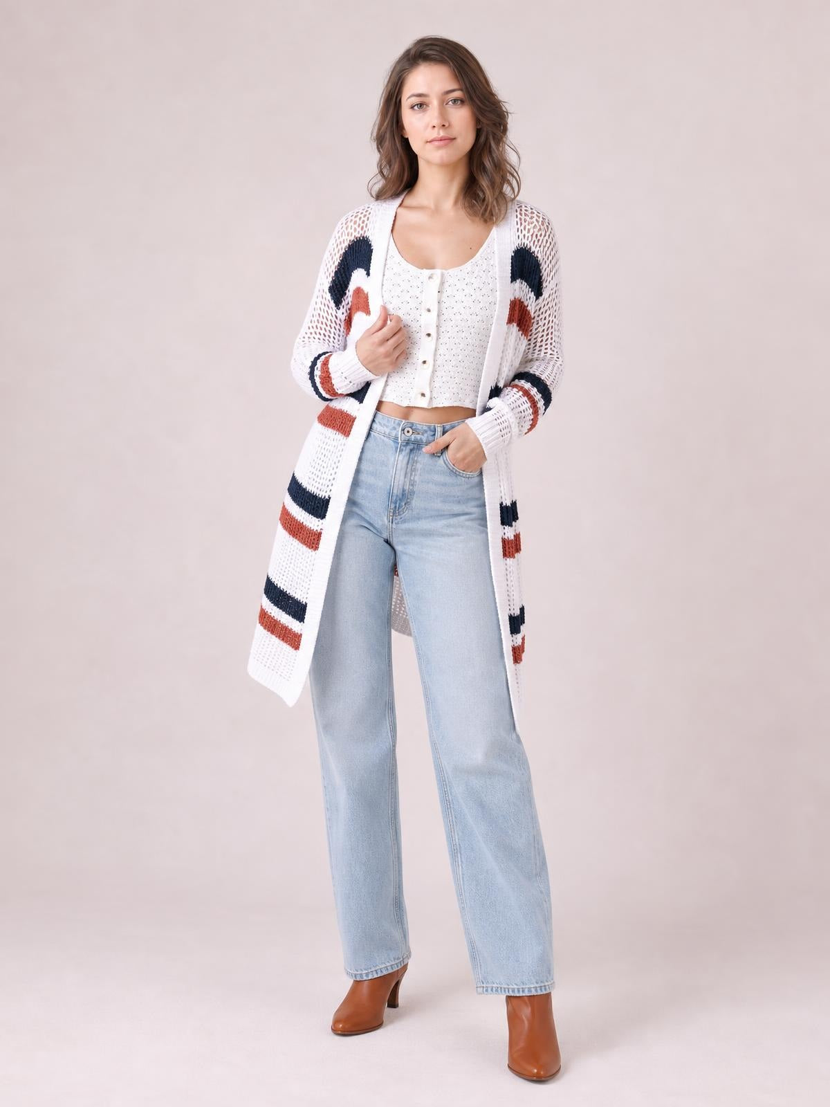 A woman models a white open front long sleeve cardigan with contrast navy and rust stripes, openwork knit, and a long relaxed silhouette.