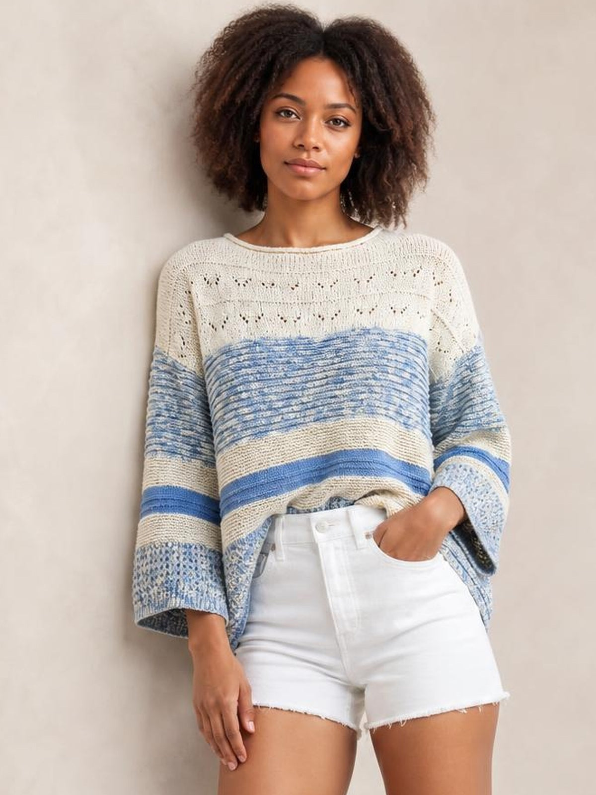 Model wears a blue and cream contrast round neck long sleeve sweater with striped knit construction, openwork details, and a relaxed silhouette.