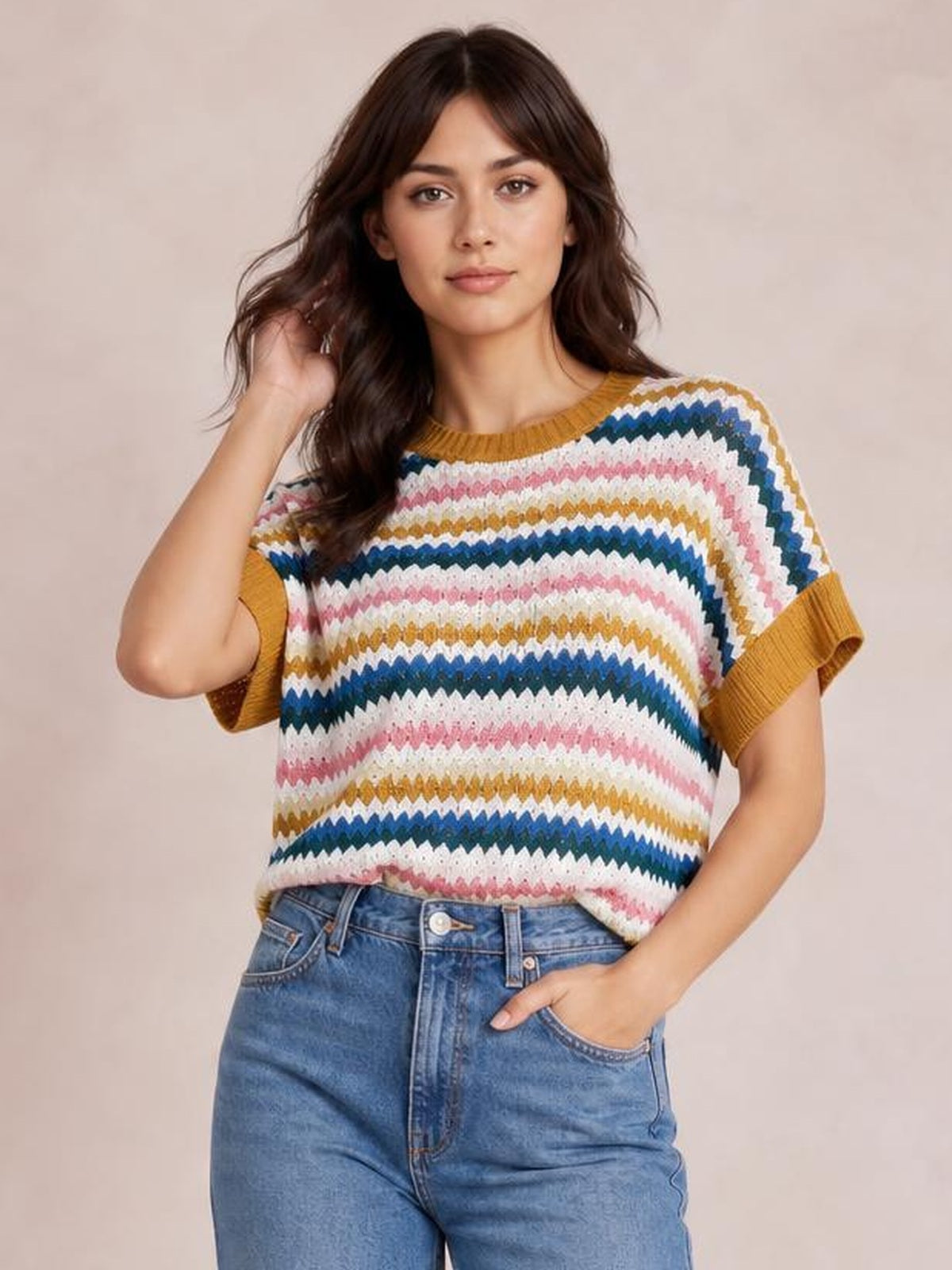 Model poses in a colorful contrast round neck short sleeve sweater with horizontal zigzag stripes, ribbed mustard trim, and a relaxed silhouette.