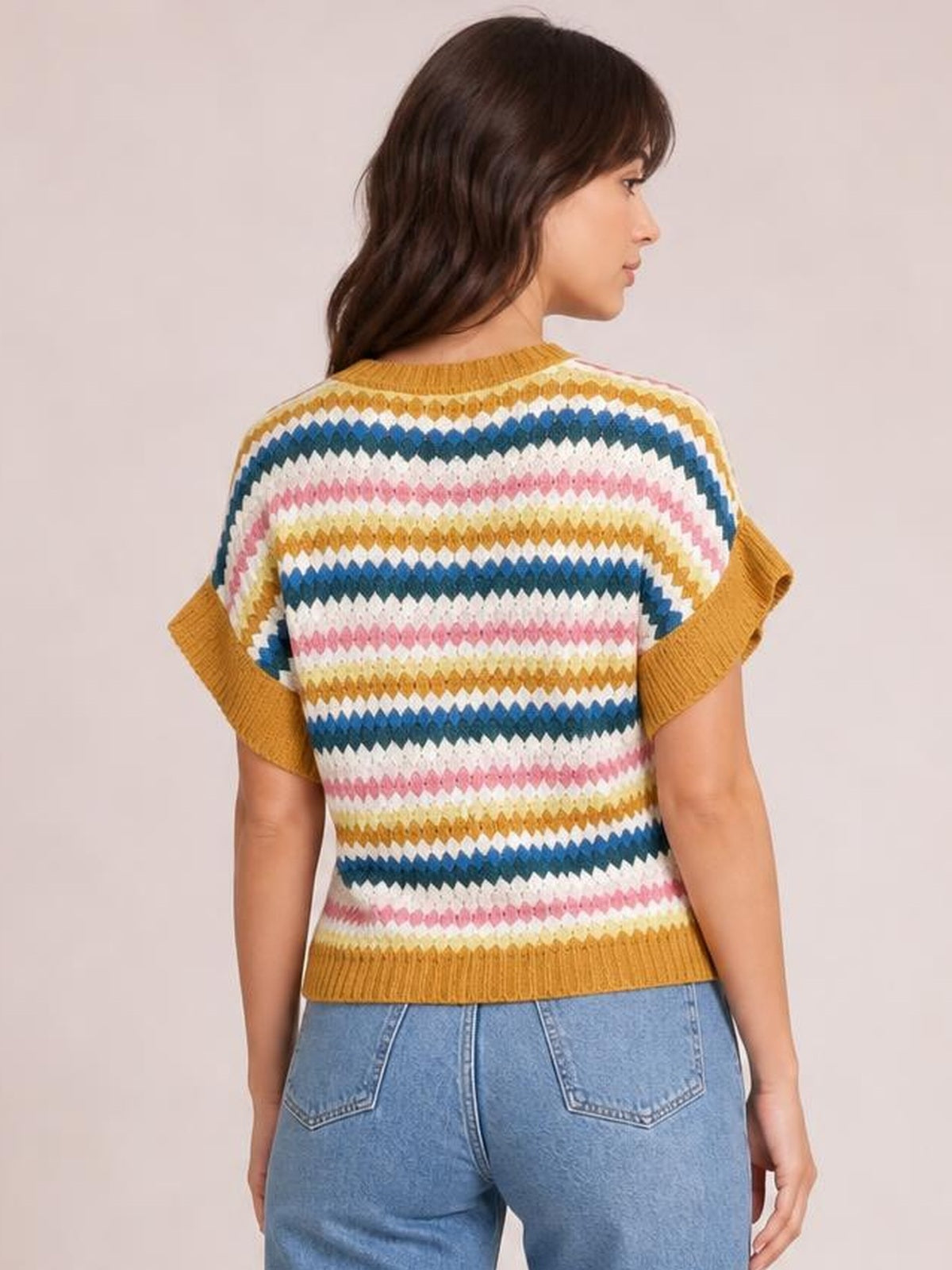 A model stands in a striped contrast sweater with a round neck, short sleeves, mustard ribbed trim, and a relaxed silhouette, shown from the back.