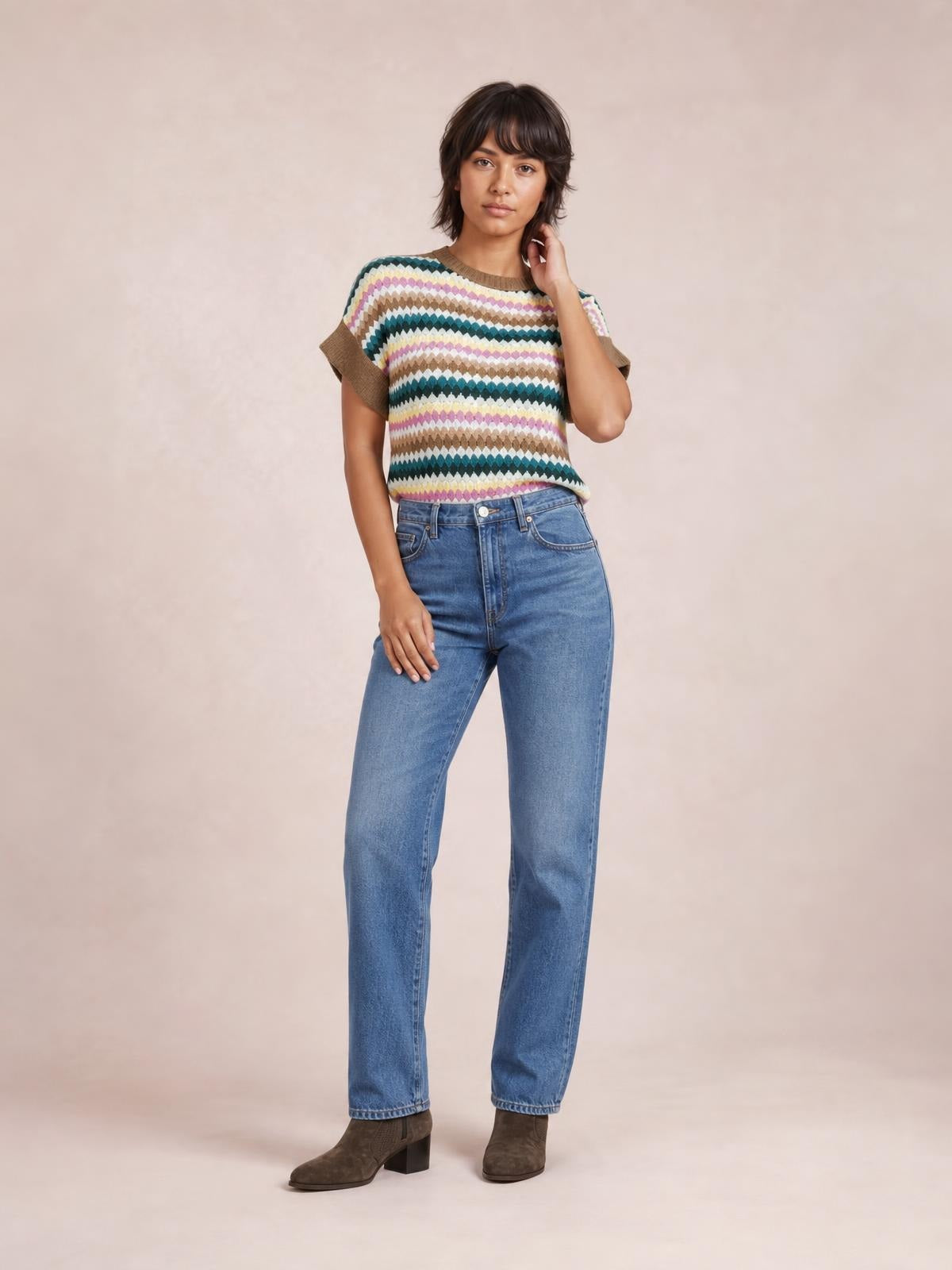 Model stands with one hand at her neck wearing a multicolor contrast round-neck short-sleeve sweater with brown ribbed trim and a relaxed straight silhouette.